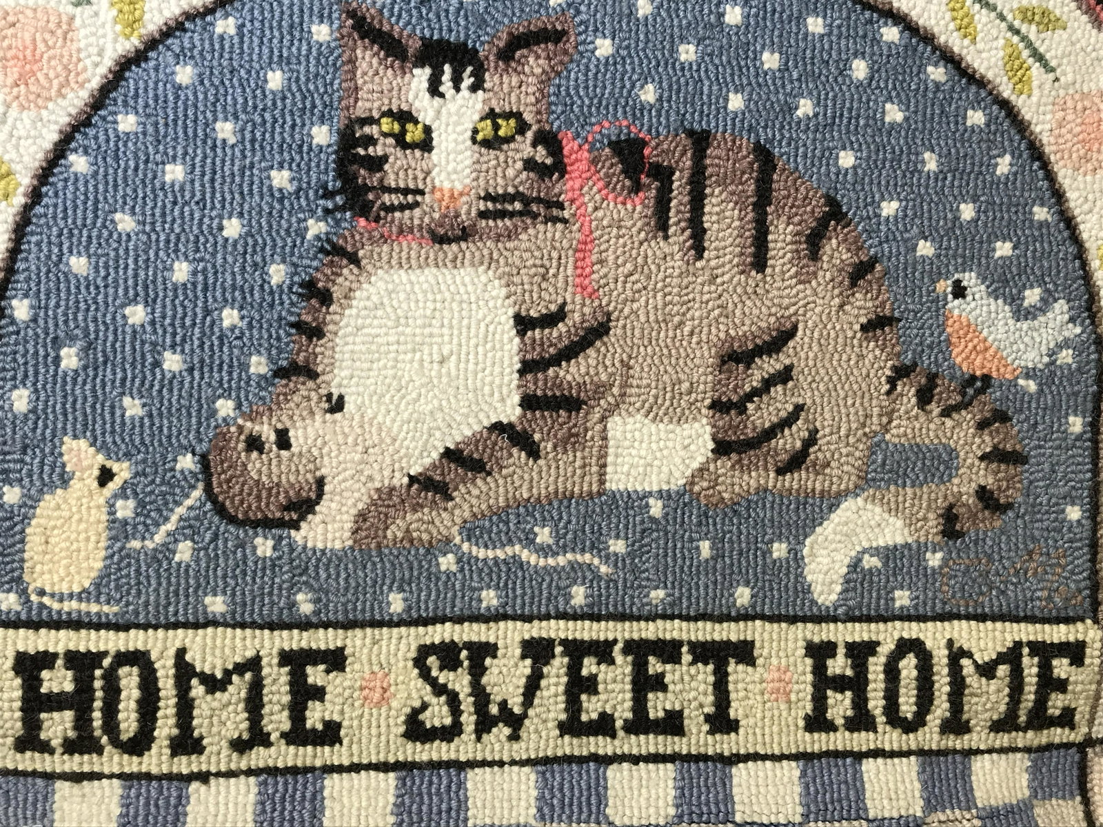 Hanging Needlepoint Welcome Mat: Hanging needlepoint welcome mat, text across the bottom reads Home Sweet Home, subject striped cat with bird and mouse, border around mat decorated with flowers and hearts, measures 24.5 at tallest po
