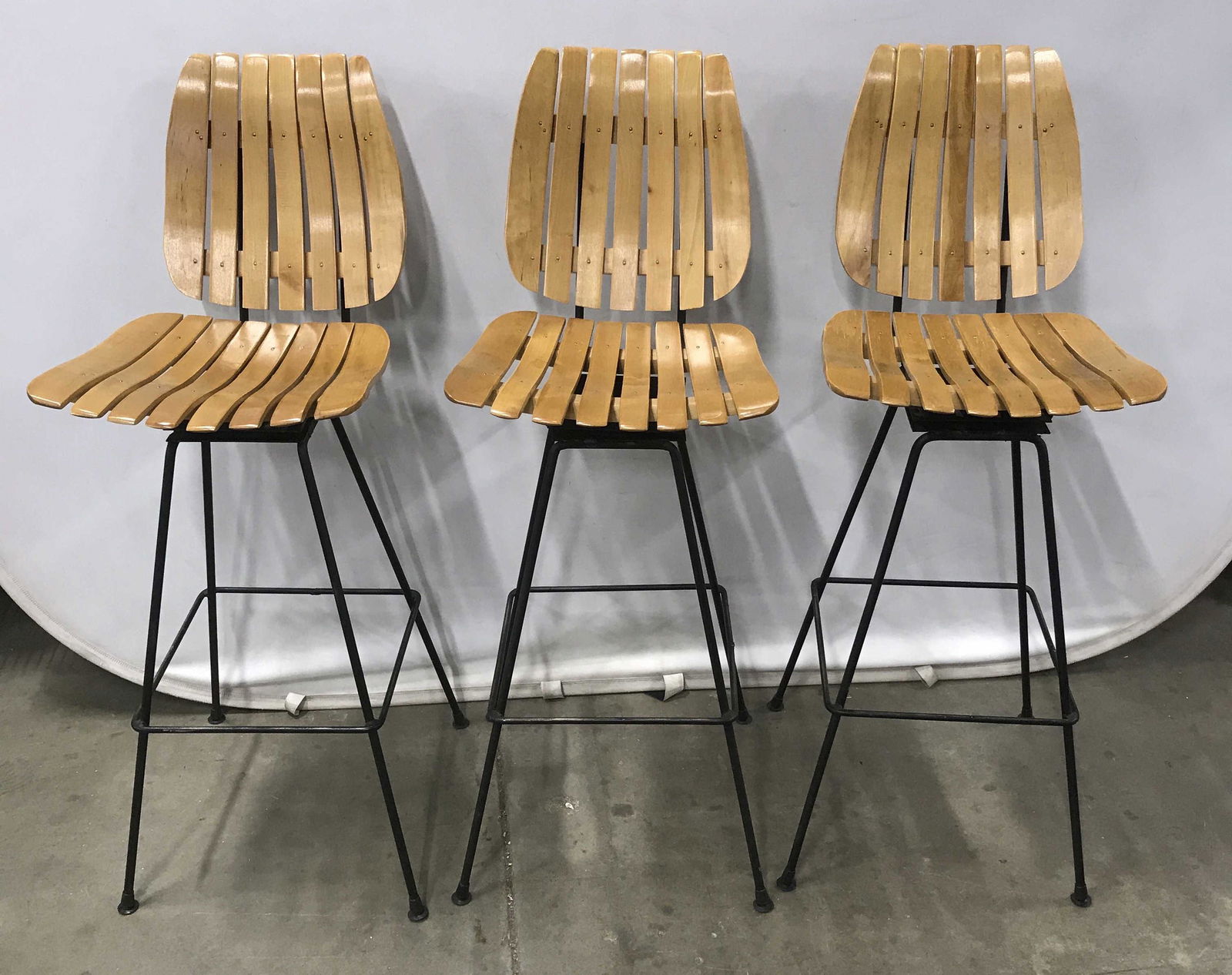 Set 3 Vintage Arthur Umanoff Style Bar Stools: Set 3 Wood and Black Toned Metal Swivel Bar Stools, slatted blond toned wooden seat and back mounted on black toned metal tubular legged base with foot rest, measures approximately 43.25 inches tall t