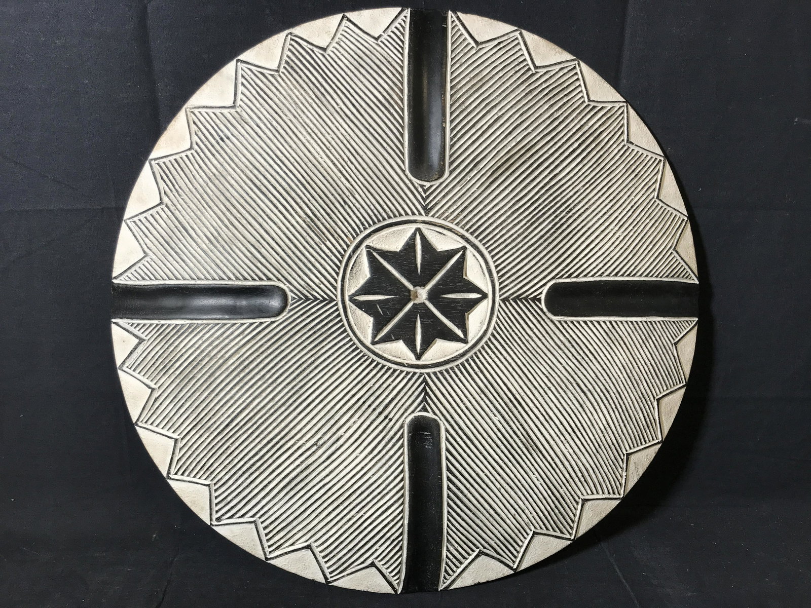Ceremonial Zulu Shield: Ceremonial Zulu Shield, origins can be found in South Africa, wooden shield with black and white paint with an 8 sided star shape carved into the front, handle carved into the back, diameter approxima