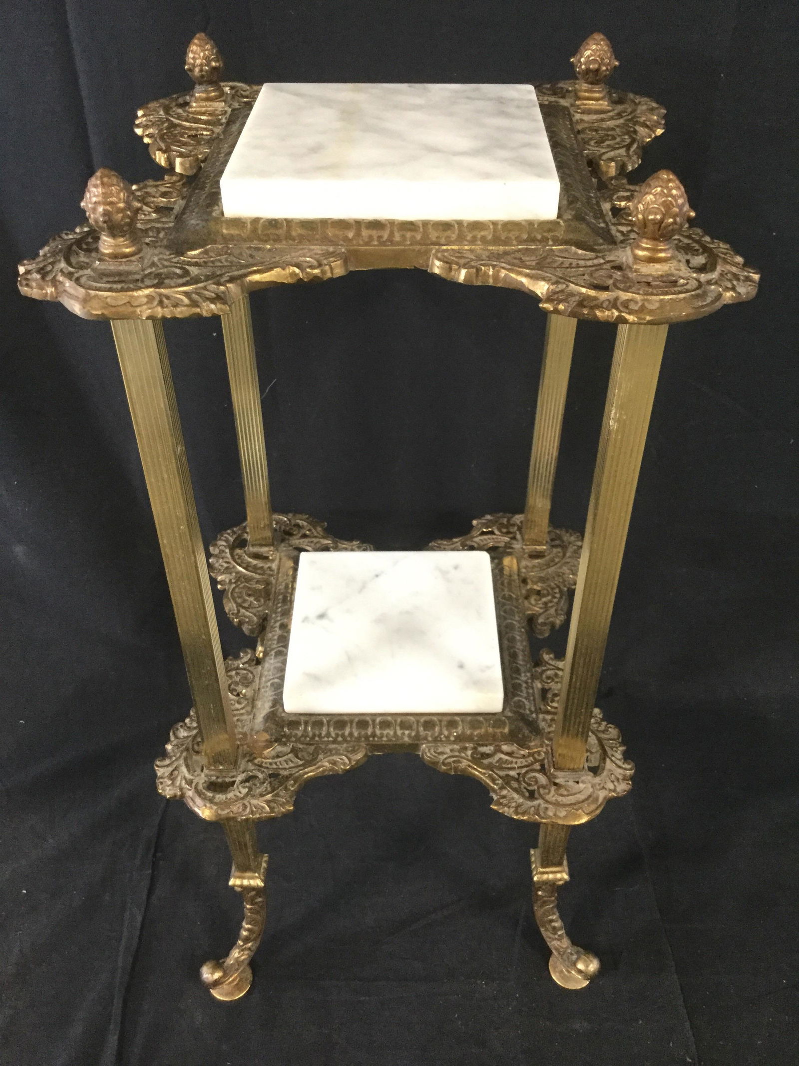 Vntge Brass Victorian Style Marble Top Side Table: Side table is gold toned and brass. Table is vintage possibly antique. Piece has white toned marble top. Piece has second lower tier with additional white toned marble area. Piece has c Scroll style f