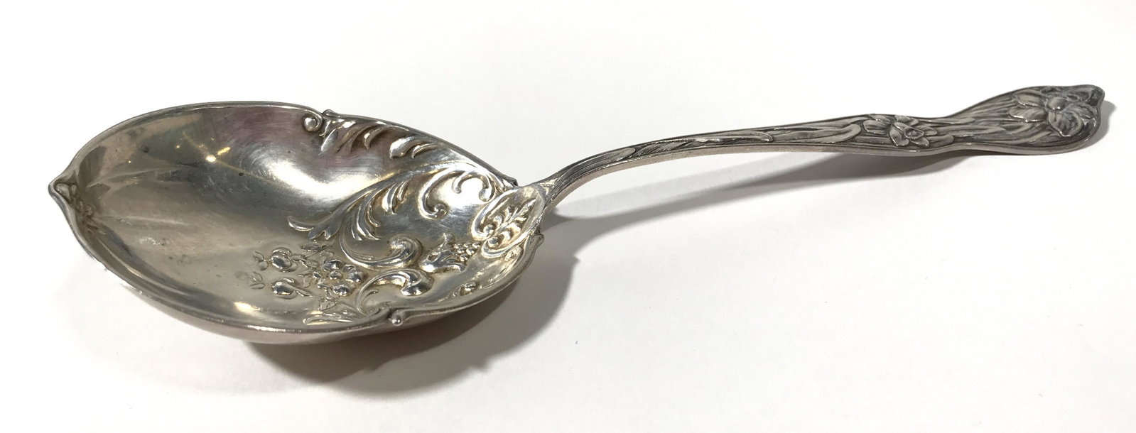 Antique MANCHESTER MFG CO Sterling Silver Spoon: Sterling Silver Serving Spoon, the piece is chased and features Repousse floral patterns in the bowl of the spoon. The piece measures approx 7.25 inches in length and 2.5 inches in width. The piece we