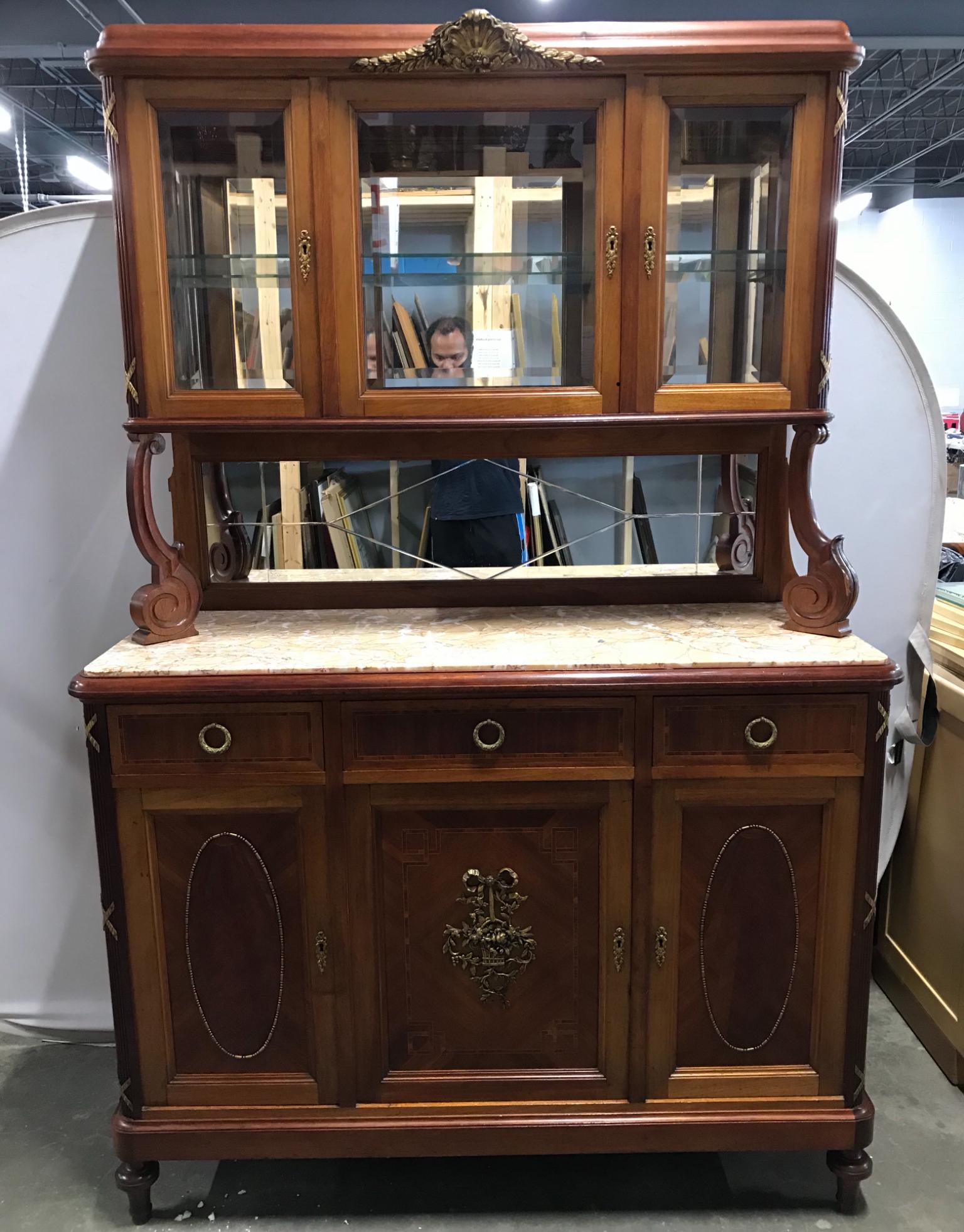 Antique Louis XVI French Walnut Cupboard: Cupboard is antique. Piece contains gilded ormolu detailing. Lower half has marble top. Cupboard has 3 cabinet doors which open to shelved storage space. Above cabinets are 3 drawers each with hand do