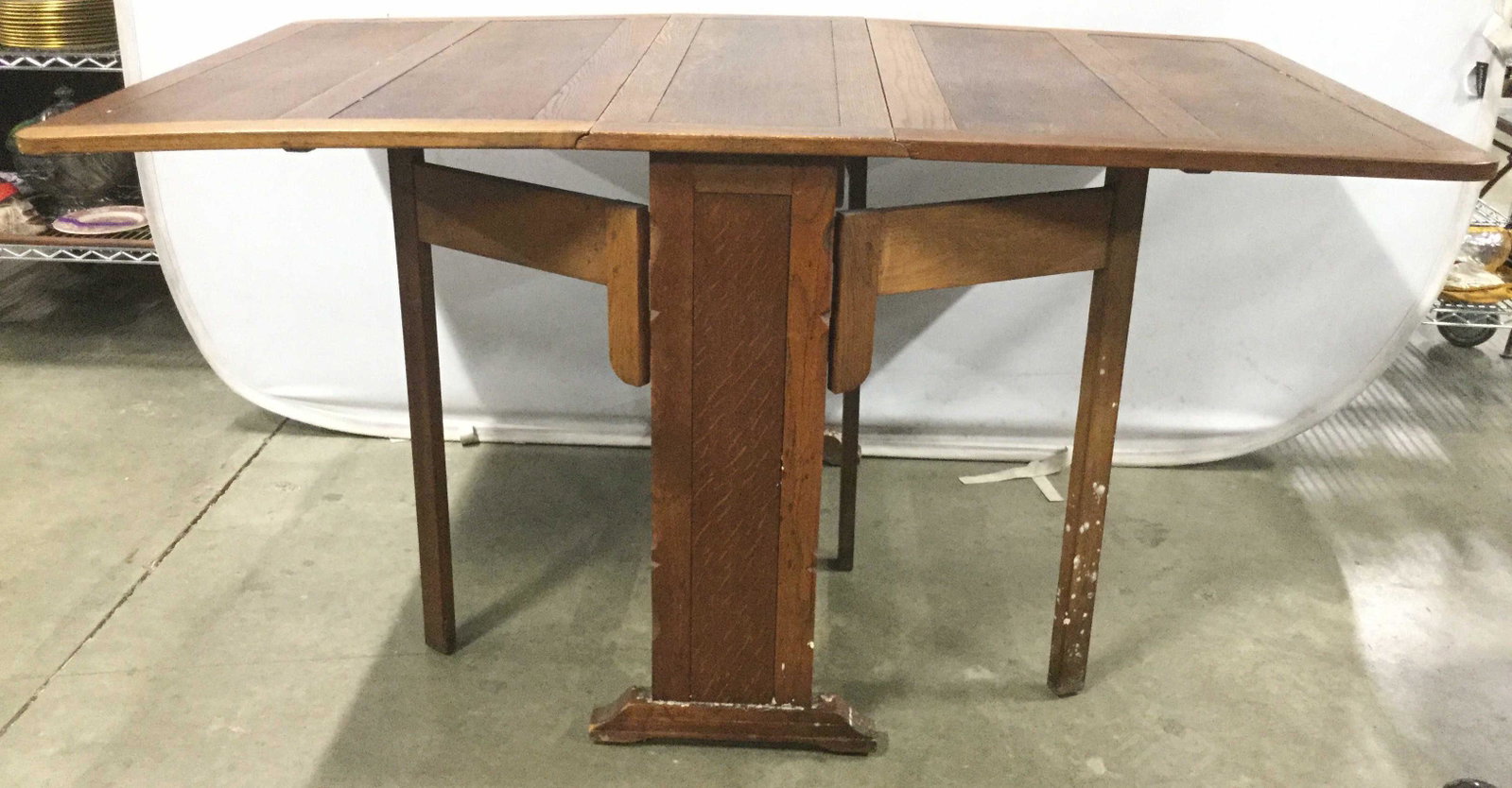 Antique Oak Drip Leaf Dining Table: Dining table is wooden and antique. Piece appears to be Oak. Table has 2 drop leaf which are held by 4 Swinging supports. When leaf are not extended, piece can be repurposed as console table. Piece me