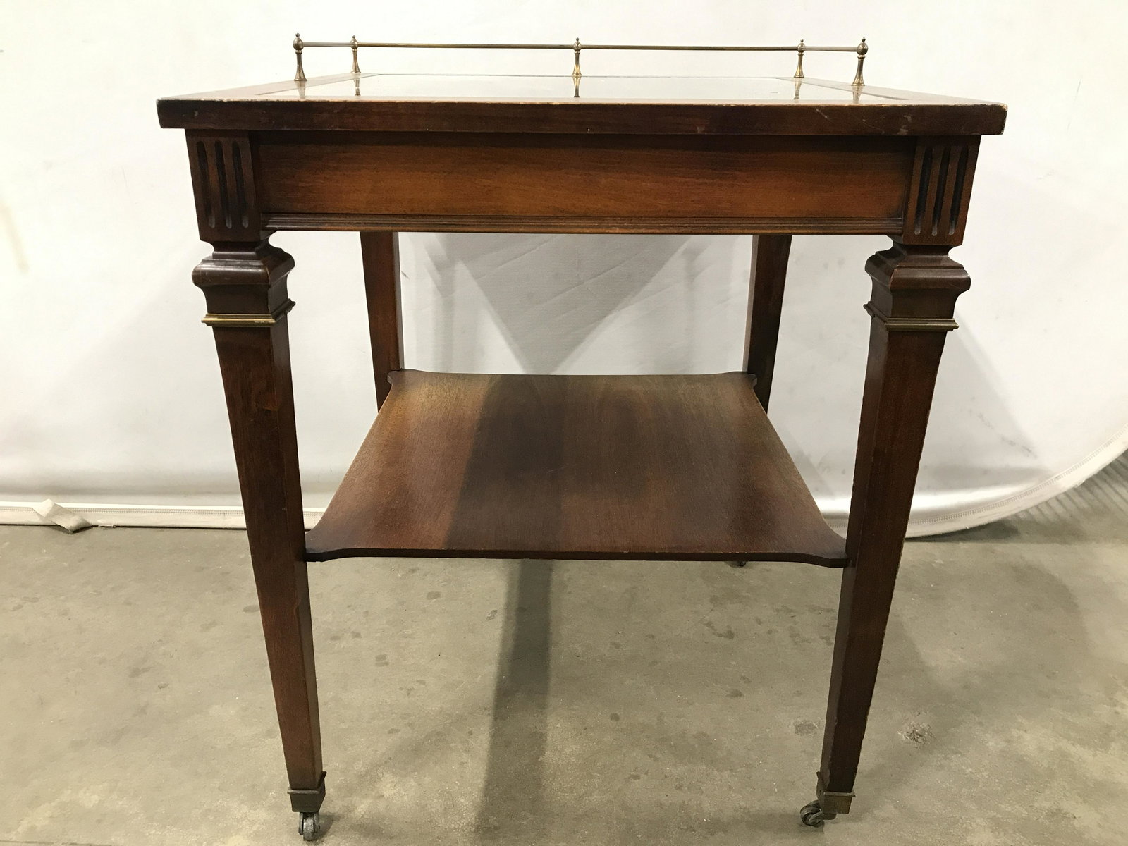 Vintage Glass Top Wooden Side Table W Casters: Side table is vintage and wooden. Piece side on 4 gold toned brass casters. Tabletop is mirrored. Top of table also has gold toned brass gallery. Side table, end table, wooden table, glass top table, 