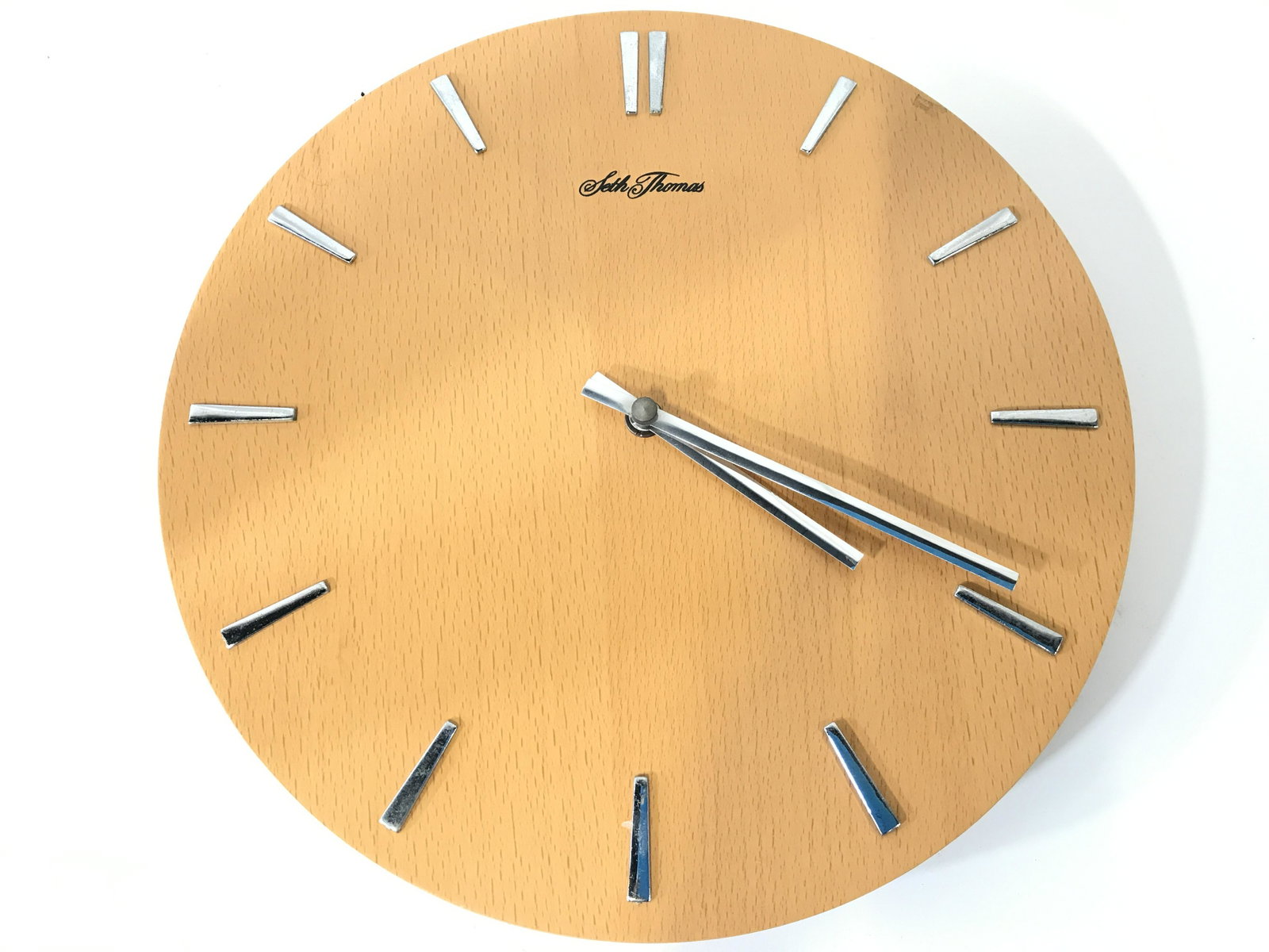 Mid Century Modern SETH THOMAS Wall Clock: Clock face is marked SETH THOMAS. Piece appears to be wooden possibly veneer. Piece is tan toned with chrome hands and number markers. Clock has circular shape. Clock, Seth Thomas clock, mid century m
