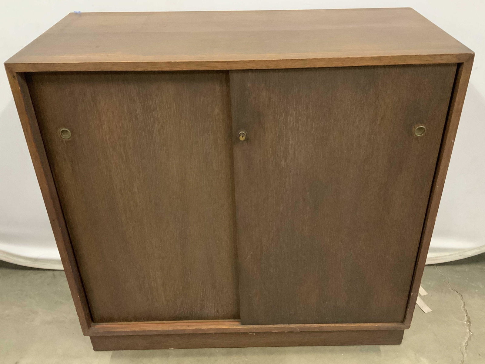 Mid Century Modern Wood Cabinet: Recessed base, cube form cabinet, credenza, side board, console , with two sliding doors, brass hardware, has wear to surface, measures ht 34 inches top 36 by 17 inches, three shelves inside for stora