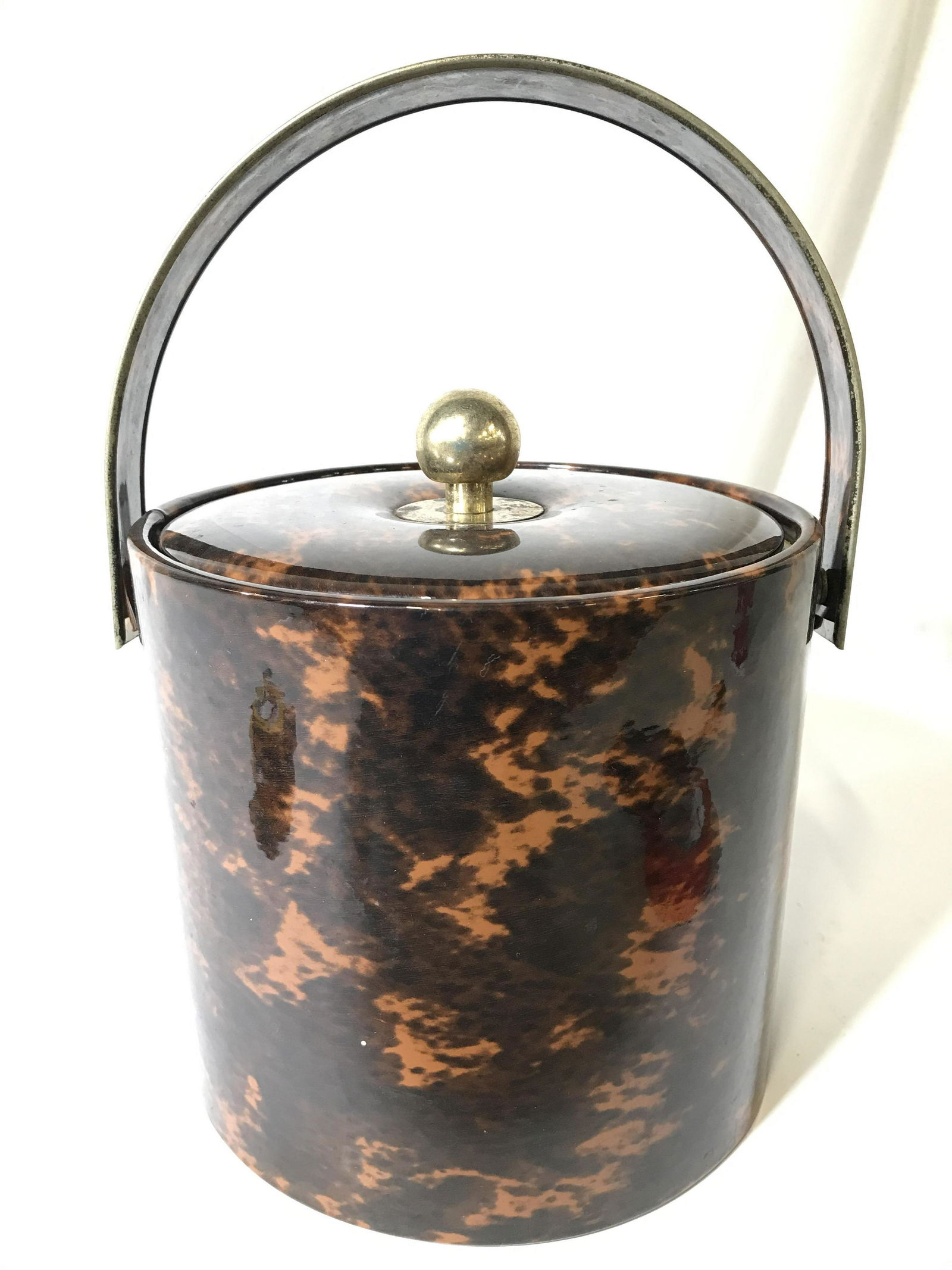 Chocolate Toned Ice Bucket W Gold Toned Handle: Ice Bucket is brown toned & lidded. Piece has gold toned arch shaped metal handle. Lid of bucket has gold toned spherical shaped handle. Piece measures approximately 12 inches tall 8.5 inches wide. Ic