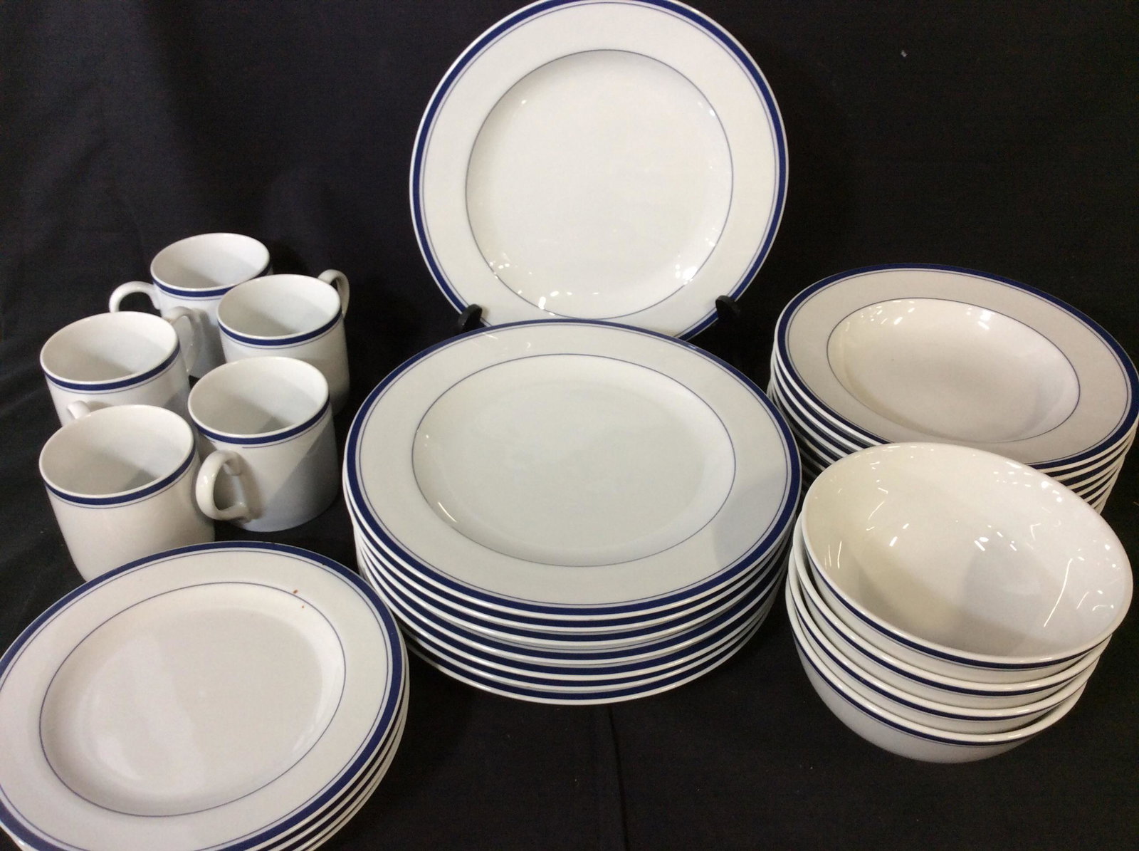 Cooks Club Everyday Porcelain Dinnerware, 29 pcs: White Porcelain Dinner Plates with navy striped rim. Set includes 8 dinner plates, 10.5 in. One plate has chip on rim. 4 luncheon plates, 8 1/4 in. Two plates have chip on rim. 8 shallow bowls. 4 deep