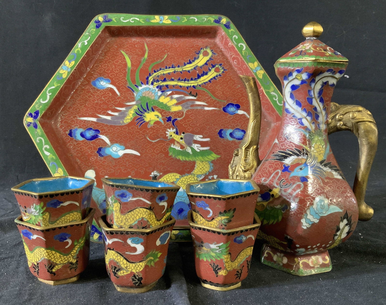 8 Piece Set Asian Cloisonne Tea Service: Set includes tray diameter app 9 inches, tea pot ht app 7 inches and 6 cups, enamel on metal red back ground with design of soaring Phoenix birds, dragons and seas, table ware, chinoiserie, tableware,