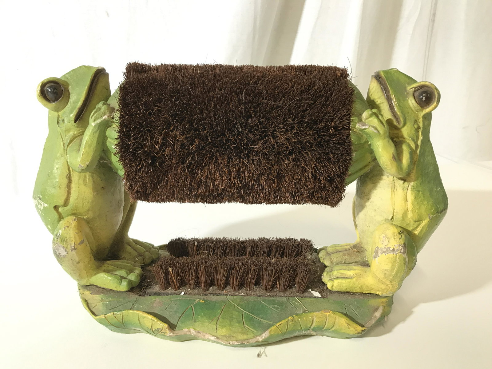 Stone Frog Themed Boot Brush: This piece is crafted from stone and hand painted. The piece resembles two frogs perched on a leaf, each frog holds and end of a brush. The top brush rotates, the bottom is fixed. There is wear presen