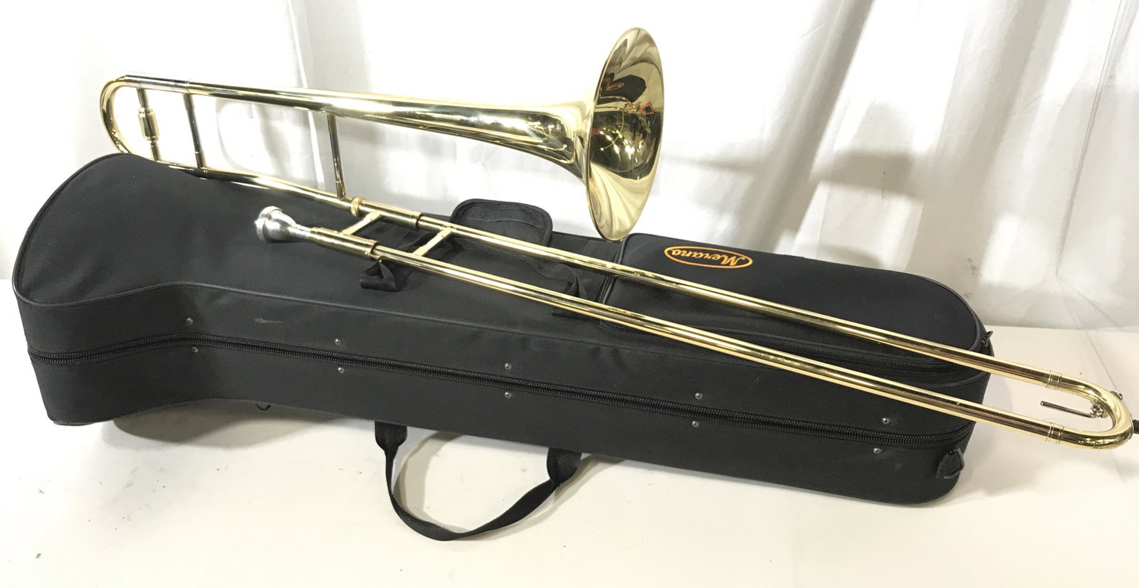 MERANO Jazz Trombone With Carrying Case: This lot includes both a jazz trombone as well as its carrying case. The trombone includes its mouthpiece, writhing the case a cleaning cloth as well as a pair of white gloves can be found. The piece 