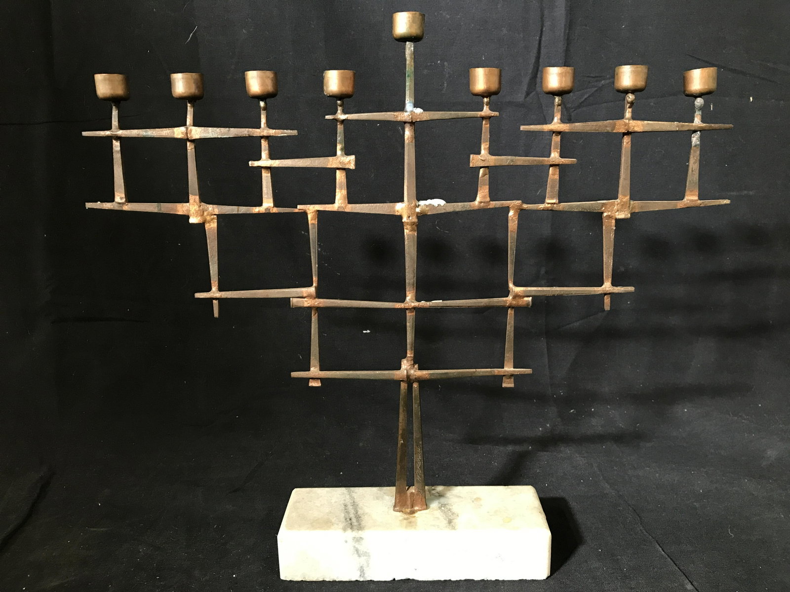 Signed Stone Base Bronze Toned Menorah: Menorah is Metal and bronze toned. Base of menorah is stone possibly marble. Piece measures approximately 13 inches tall 15 inches long. Menorah is signed illegibly. Menorah, Judaica, Hebraica, tablew