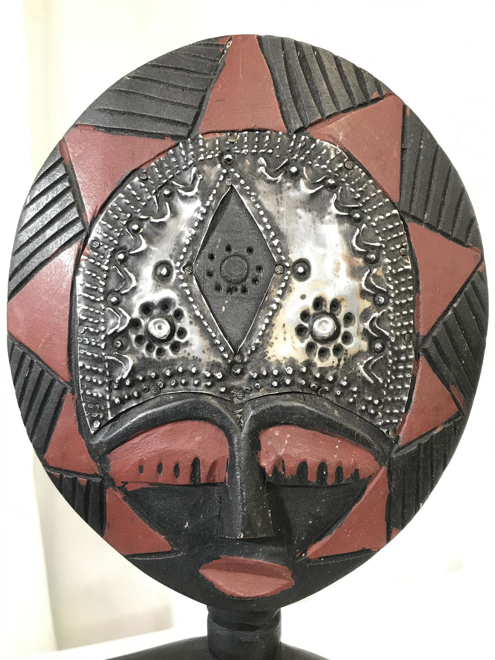 Carved Wooden African Fertility Sculpture: Fertility sculpture is black, red, and silver toned. Piece appears to possibly be hand painted and hand carved. Center of head are is metal. Piece depicts a seated figure. African sculpture, fertility