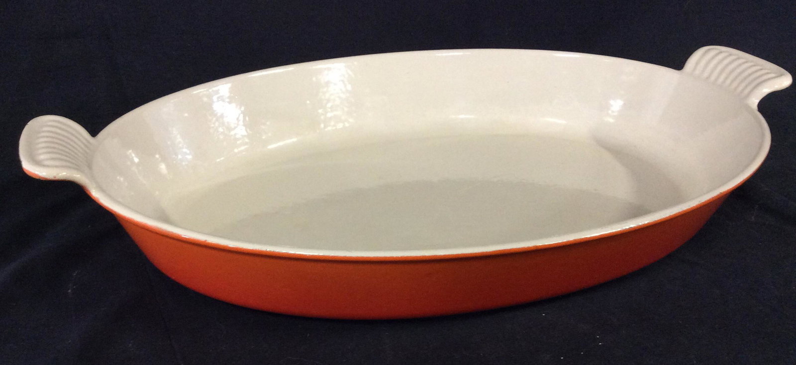 Le Creuset Heritage Stoneware Oval Gratin, France: Casserole Dish, Bakeware, Ovenware with carry handles, underside orange, measures 16 1/4 in Long, 10 1/4 in wide. Durable porcelain enamel-glaze finish is easy to clean, is exceptionally strong and en