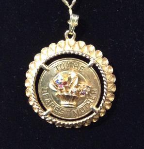 Gold Tone ‘Dearest Mother’ Medallion Pendant: 1 3/4 in. Reticulated Rim pattern, brushed metal, center floral basket with crystals. Inscribed ‘To The Dearest Mother’ . Attached stretch rope ( thins out toward end) . Mother Pendent , Costume J