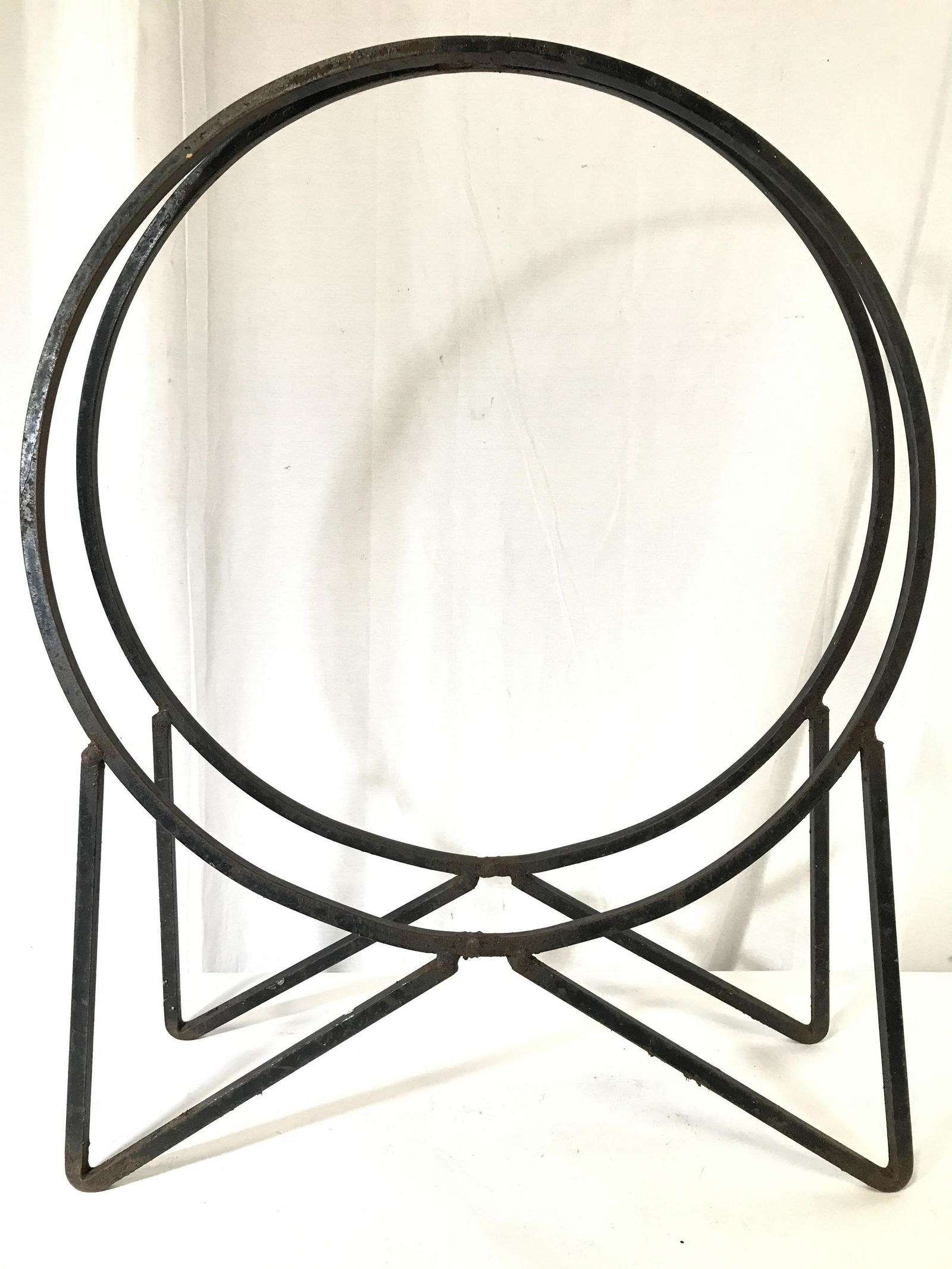 Black Toned Metal Sculpture: Piece is metal and black toned possibly iron. Piece may be up cycled firewood holder. Piece has circular shape with triangular shaped feet. Piece measures approximately 30.5 inches tall 25 inches wide