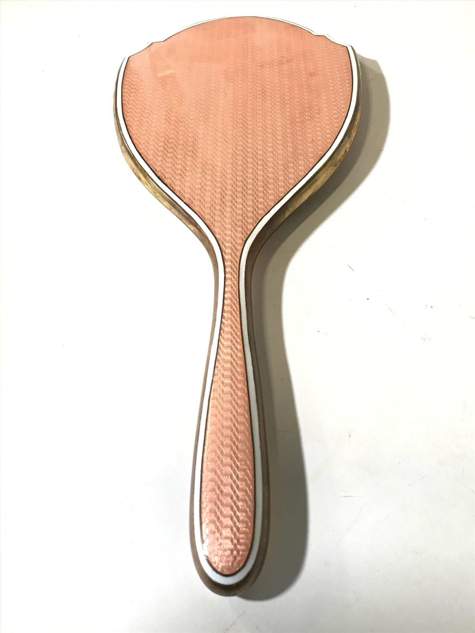 Antique French Enamel Hand Mirror: Mirror is vintage possibly antique. Mirrored surface is oval shaped and beveled. Piece appears to be enamel and brass. Piece has tones of peach, white, and gold. Piece measures approximately 12 inches