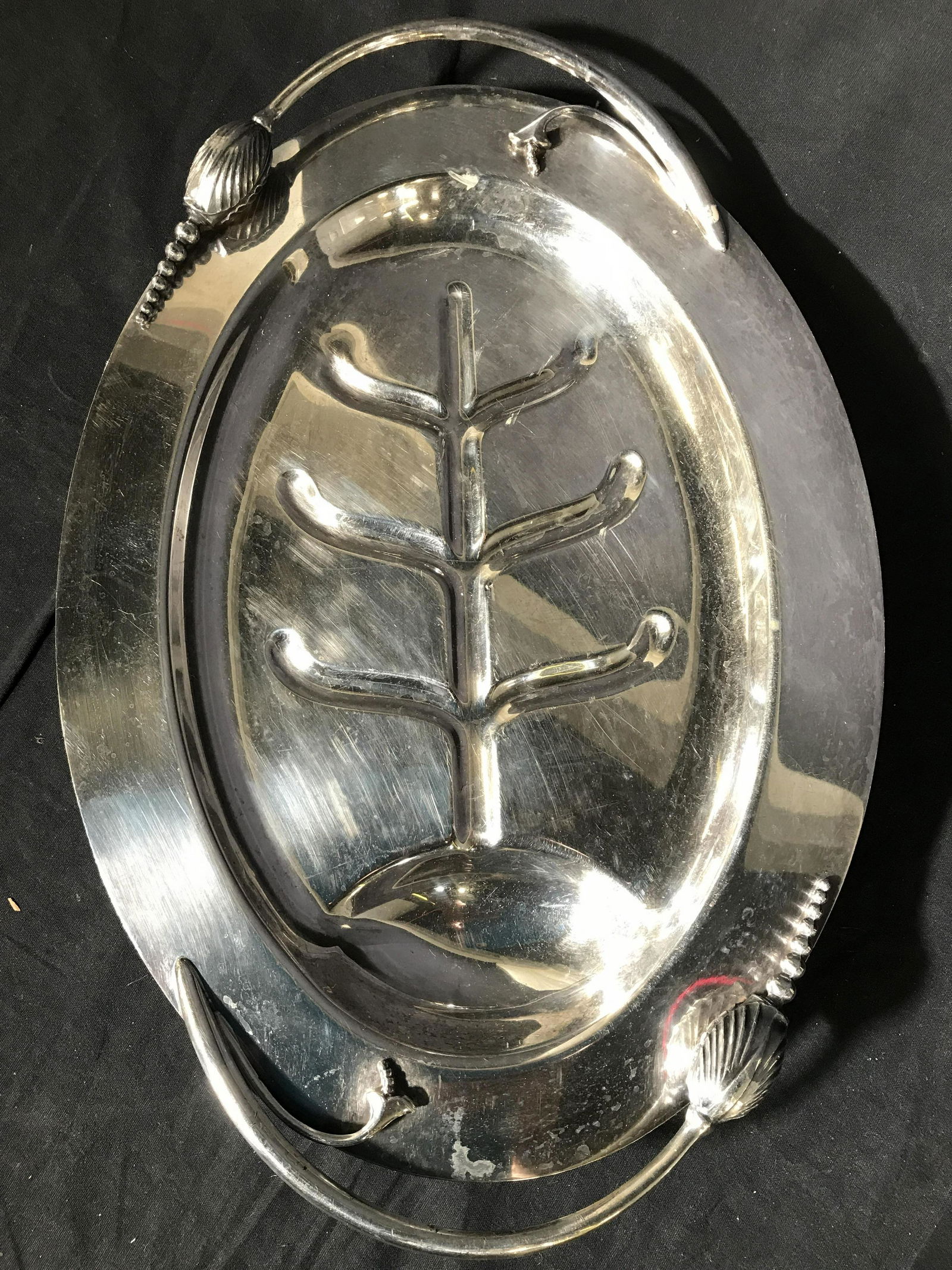 Silver On Copper Footed Fish Plate: Underside of piece is marked SILVER ON COPPER. Piece has curved floral detail handles. Piece measures approximately 17 inches long 12 inches deep, 2.5 inches tall. Fish plate, fish serving dish, handl