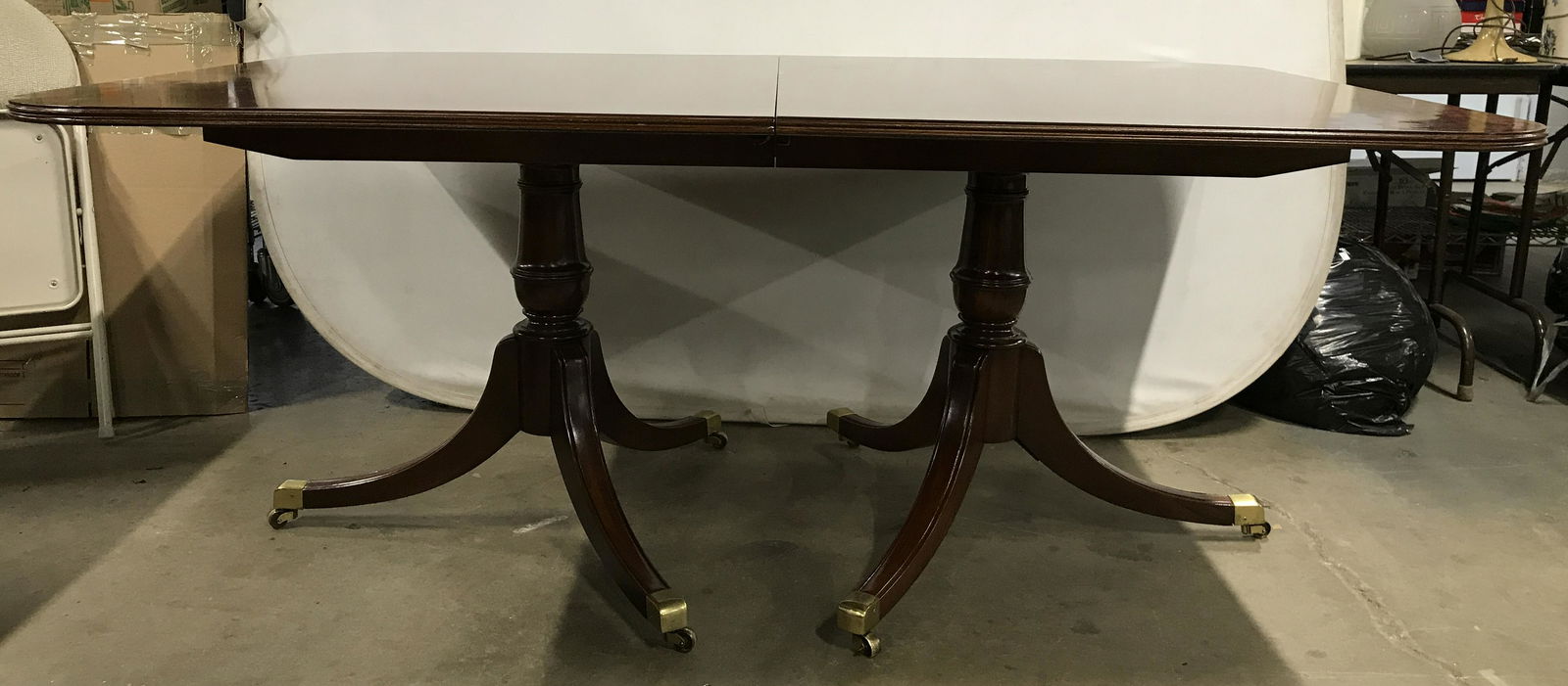 Vintage Double Pedestal Wooden Dining Table: Dining table is wooden. Piece is vintage possibly antique. Pedestals each sit on 3 gold toned brass casters. Piece Measures approximately 116 inches long with leafs 72 without 30 inches tall 46 inches