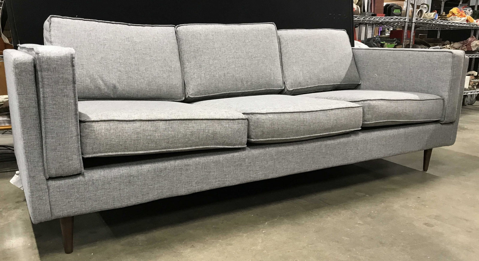 GUS Mid Century Modern Slate Toned Sofa: Underneath cushion has tag which reads GUS. Sofa is grey toned. Piece has 3 seat cushions & 3 backrest cushions. Piece has brown toned feet. Sofa, couch, Grey couch, grey sofa, mid century modern sofa