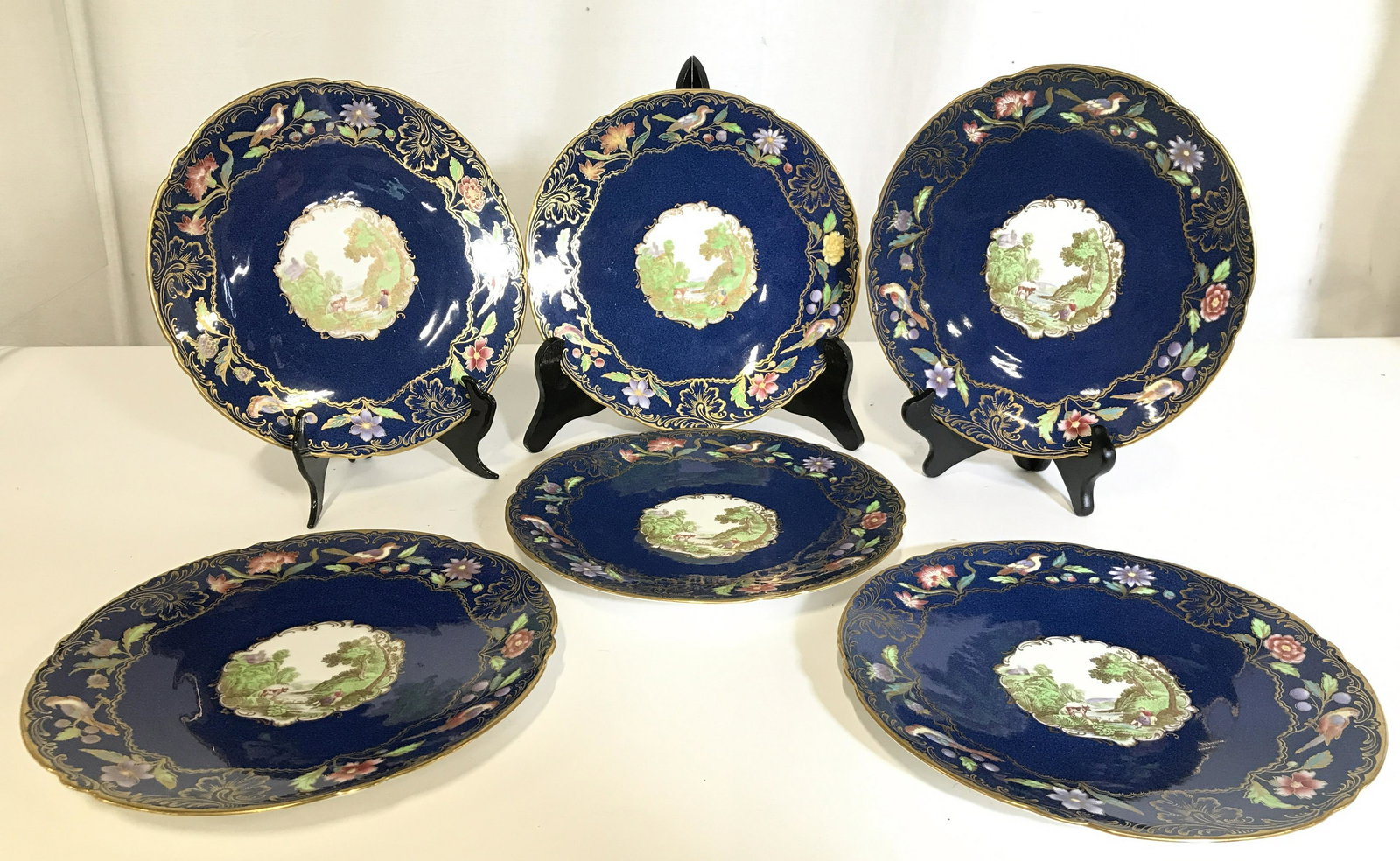 Set 6 SPODES COPELAND Porcelain Plates: Undersides of plates are marked SPODE COPELANDS CHINA ENGLAND. Each plate is blue toned with gold toned ornate detail, in addition to multi toned floral, leaf, & bird detail, & depiction of a Figural 