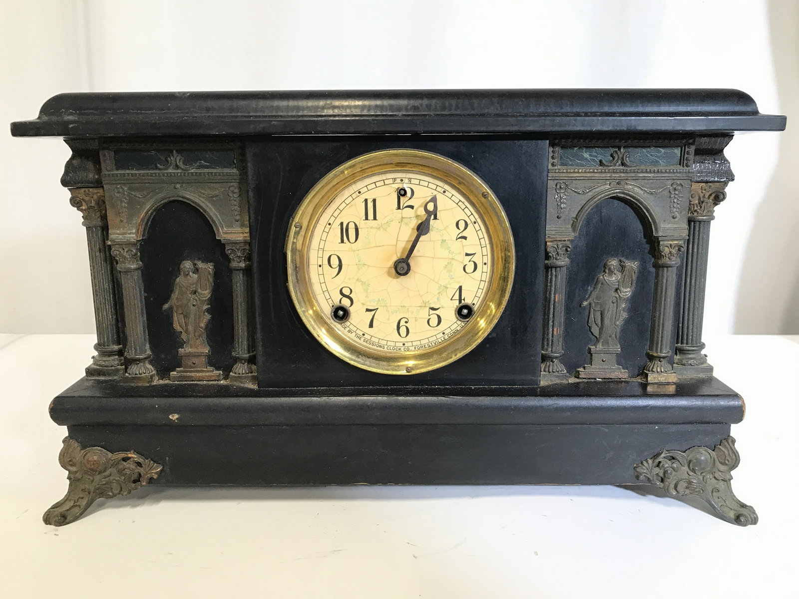 THE SESSIONS CLOCK CO Vintage Mantel Clock: Clock face reads MADE BY THE SESSIONS CLOCK FORESTVILLE CONN US. Mantel clock is black toned and wooden. Piece also has column detail on each side. Clock has angelic Figurals with harp on each side. P