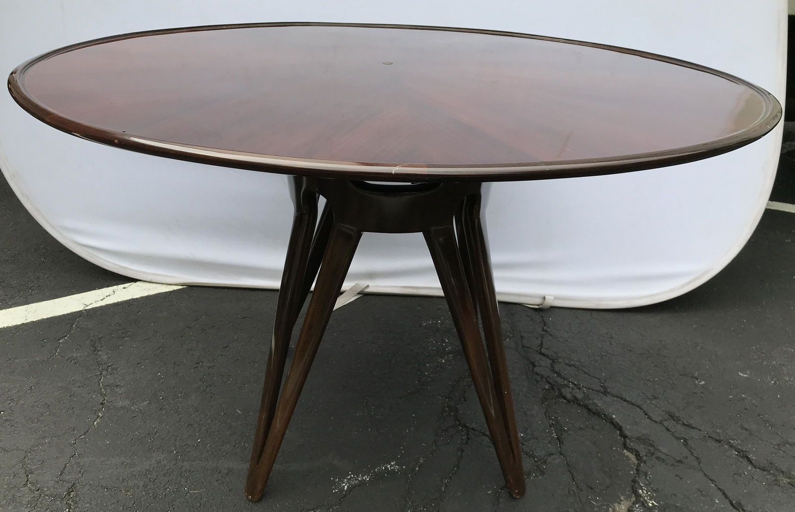 Hair Pin Leg Style Mid Century Modern Dining Table: Table is wooden. Piece is mid century modern. Piece has carved wooden pedestaled base with hair pin style splayed legs. Tabletop has round shape. Table top appears to possibly be inlaid. Edges of tabl