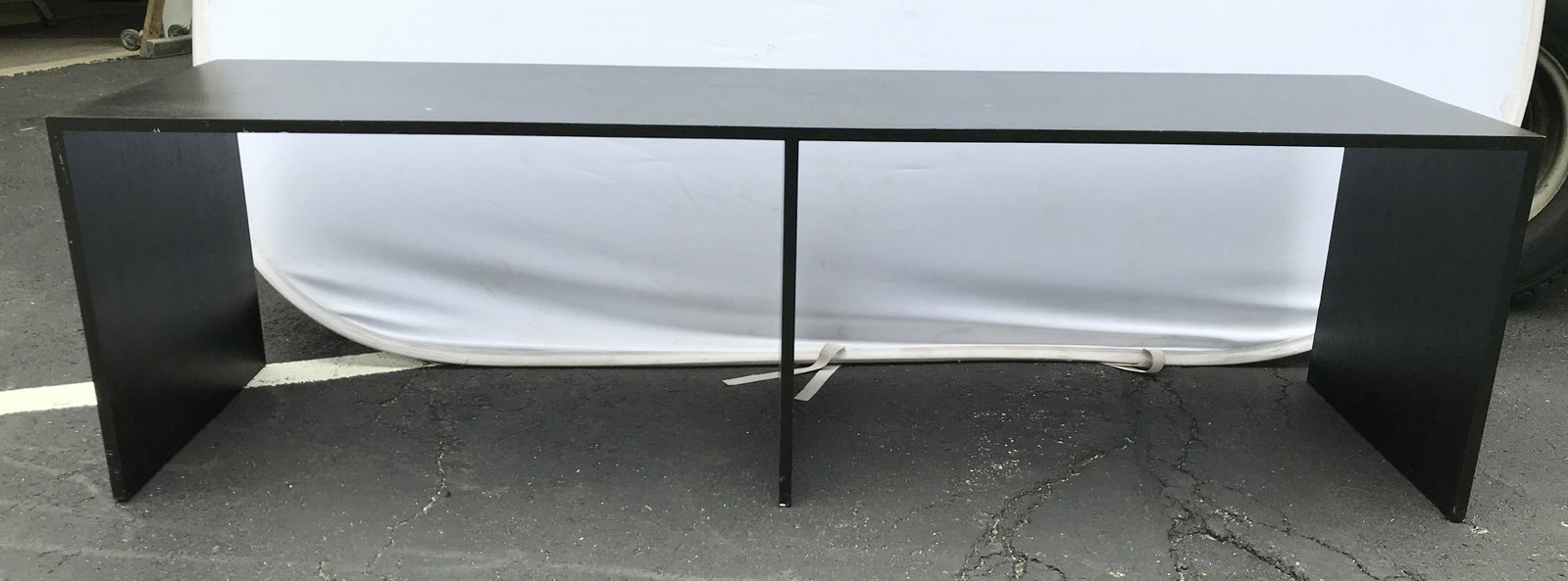 Black Toned Wood Veneer Console Table: Table is black toned, appears to be wooden possibly veneer. Measures approximately 72 inches long 21 inches tall 20 inches deep. Console table, wooden table, black table, black console table, hallway 