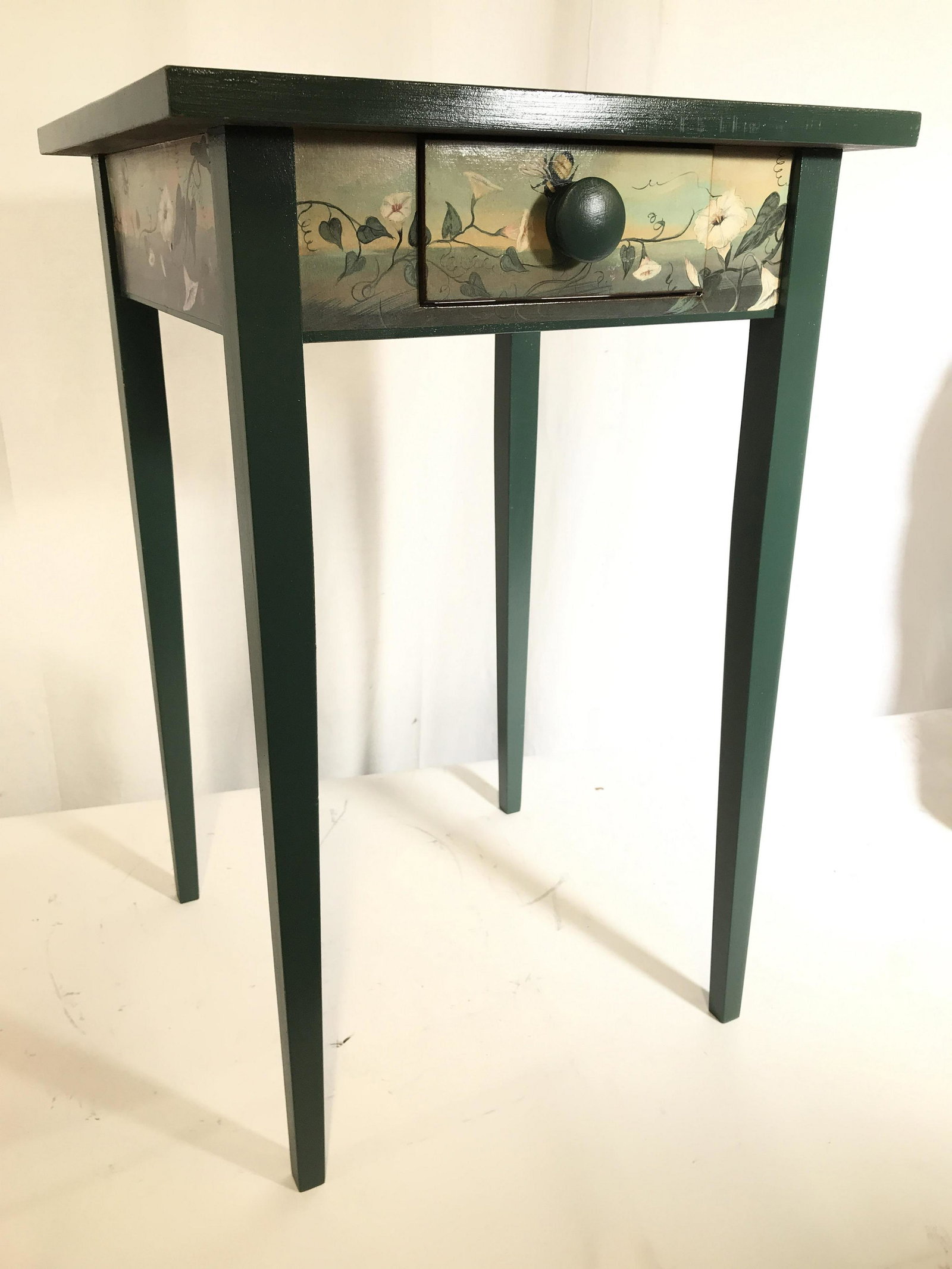Artisan Made Wooden Decoupage Side Table: Piece is an artisan made side table/end table with small drawer, decorated with flowers, rabbits, chipmunk, squirrel and bumblebee. Side table has 1 drawer with green toned carved wooden knob style ha