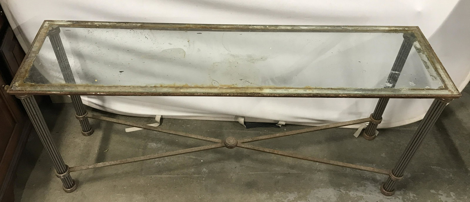 Antique Metal Glass Top Console Table: Console table is antique. Piece has metal frame and glass top. Measures approximately 59 inches long 27 inches tall 16 inches deep. Piece has column style legs and stretchers in between legs. Console 