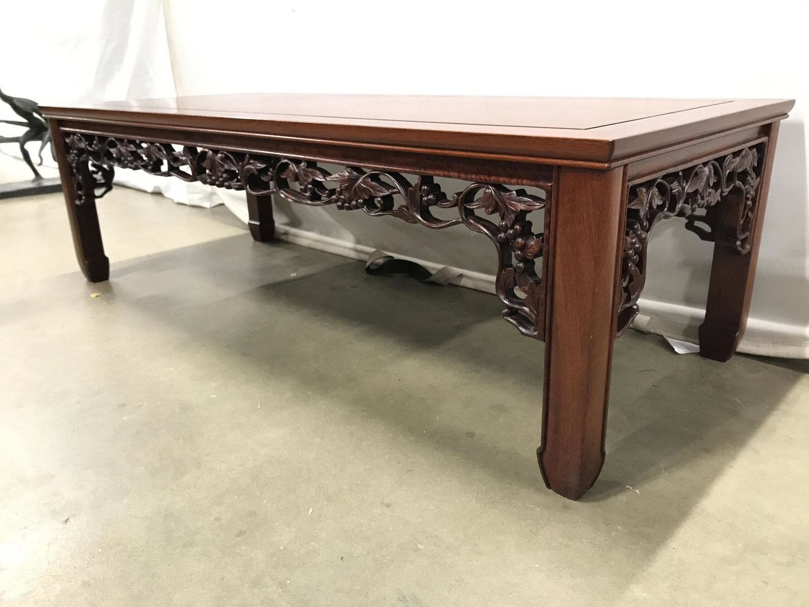 Antique Carved Wooden Chinese Coffee Table: Coffee table is antique. Piece is wooden. Contains intricately carved grape, leaf & vine detail. Piece has carved wooden feet. Piece is possibly cherry wood. Piece measures approximately 54 inches lon