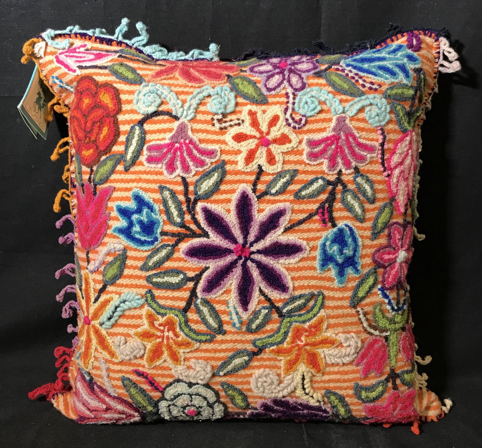 Karma Living Wool Embroidered Floral Pillow: Karma living 100% wool pillow, subject a orange striped pillow with floral designs embroidered on the front, multi colored fringes to the sides, tan linen backing, tag to corner reads ‘Karma Living�