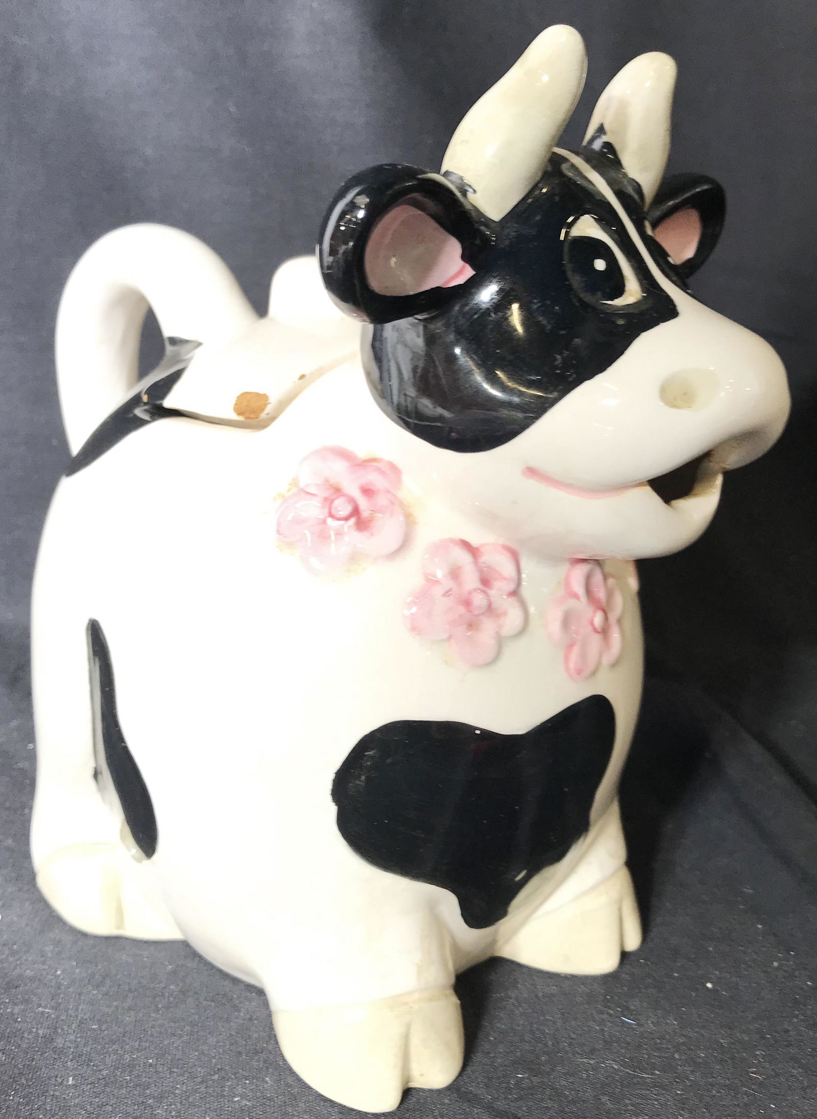 Vintage Porcelain Lidded Cow Pitcher: Lidded. Dish has shape of cow. Piece has pink toned floral detail on front. Piece appears to possibly be hand painted. Piece measures approximately 7.5 inches tall and deep 4.5 inches wide. Piece bass