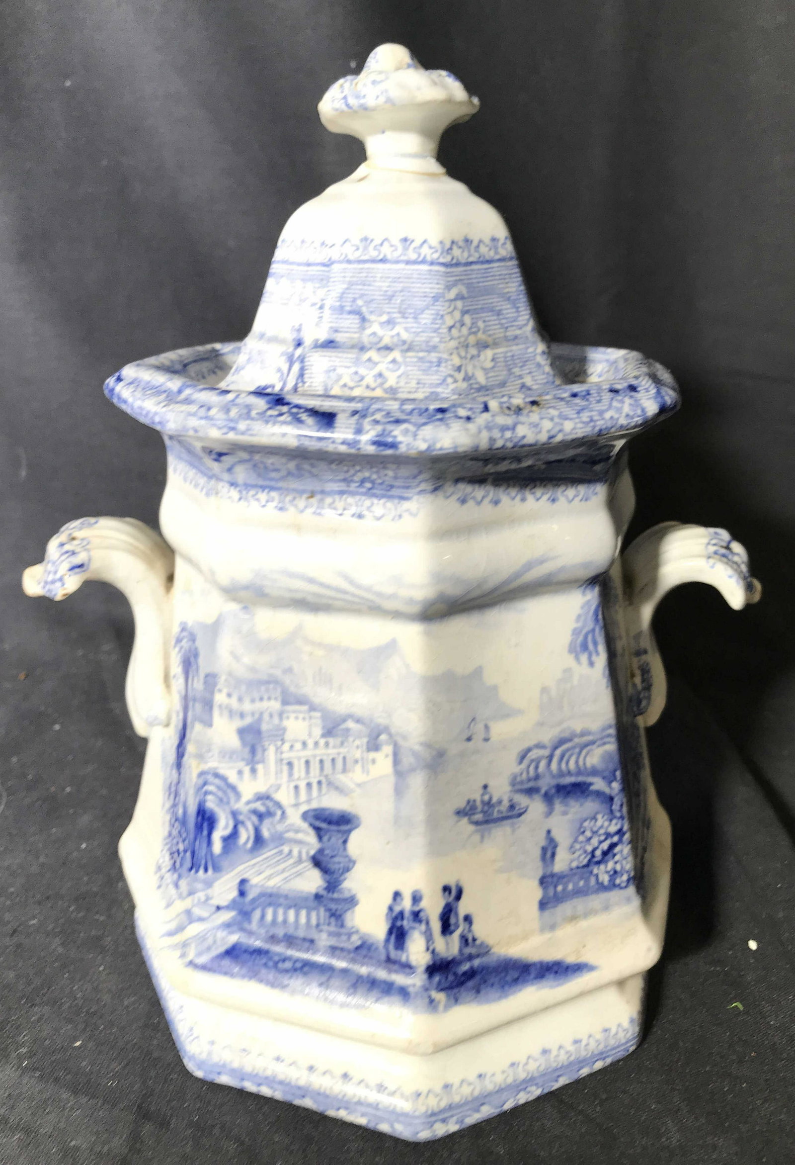 J WEDGWOOD COLUMBIA IRONSTONE Lidded Jar: Underside of piece is marked J WEDGWOOD COLUMBIA IRONSTONE. Jar includes lid. Piece also has handle on each side. Piece is white toned with blue toned depiction of city. Piece measures approximately 8