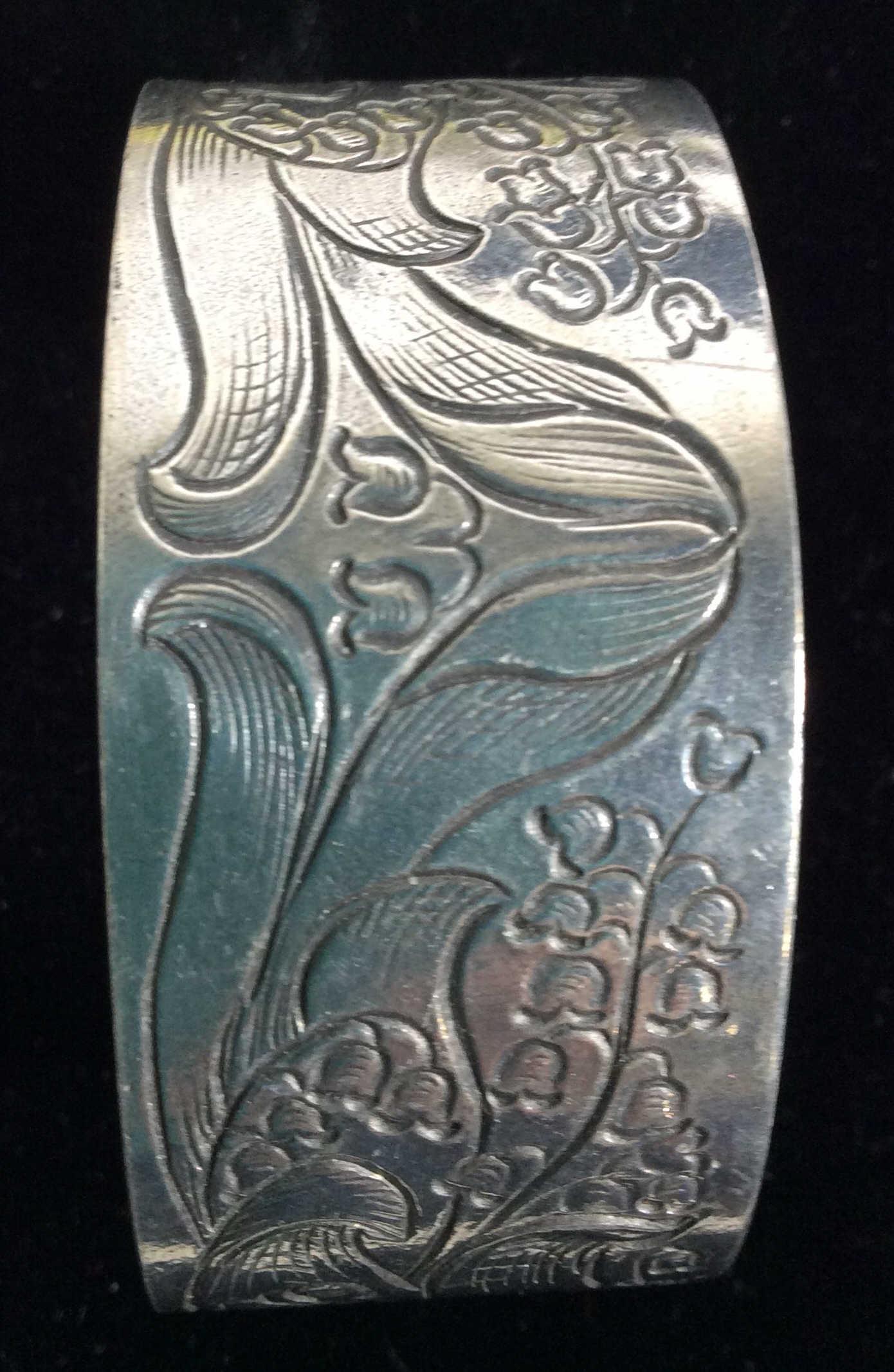 Signed Salisbury Pewter Etched Lilly Bracelet: etched Lilly of the valley flowers Underside impressed ‘Salisbury Peter’ and the Word ‘ May’ engraved. Band width 1 1/8 in. Length 6.5 in. Salisbury Pewter Lilly of the valley cuff bracelet, P