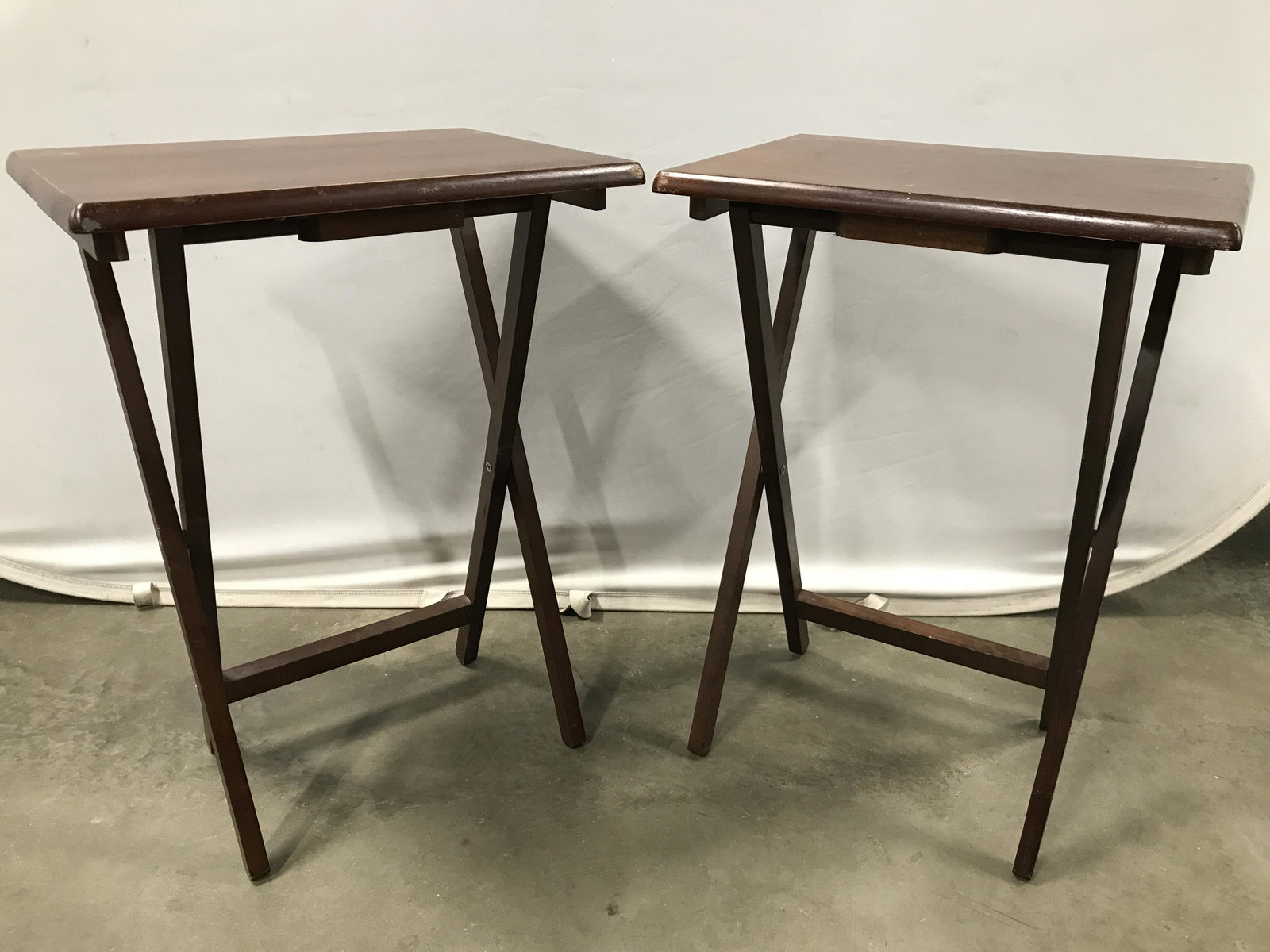 Pair Brown Toned Vintage Tray Tables: Tray tables are brown toned and wooden. Tables are foldable. Tray tables, snack tables, wooden tray tables, wooden snack tables, foldable tray tables. Each piece has significant wear consistent with a
