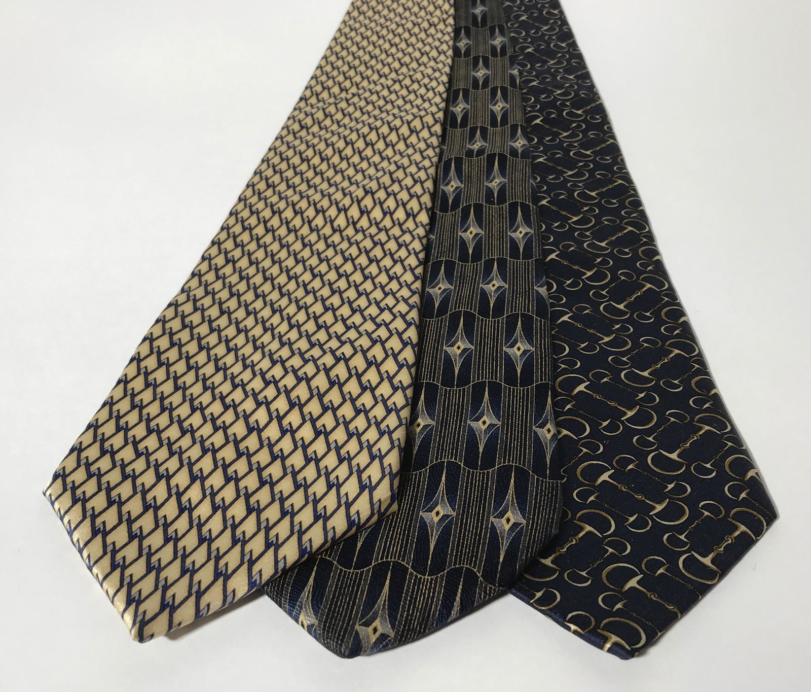 Lot 3 Blue & Gold Toned Neckties: Lot Three vintage men’s neckties. The ties are navy blue and gold toned, each tie is from a different designers. Designer labels include: LOUIS FERAUD, GIORGIO, AND BARRINGTON. Giorgio label also re