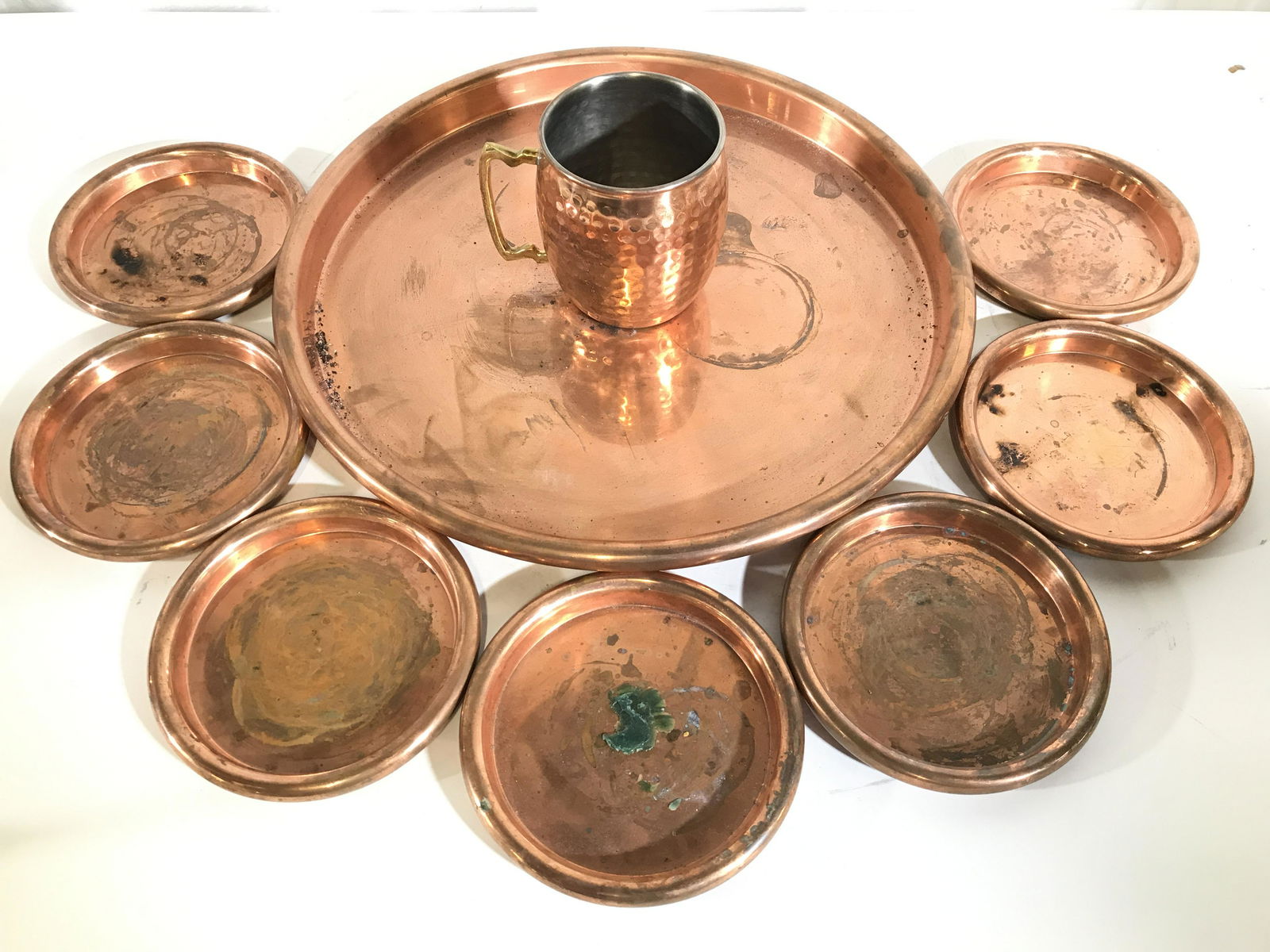 Lot 9 Copper Toned Tabletop Accessories: Lot includes 7 coaster 1 mug, & 1 serving dish. Each appear to be copper. Serving plate measures approximately 14.5 inches wide. Copper tabletop, copper tableware, vintage copper, vintage copper table