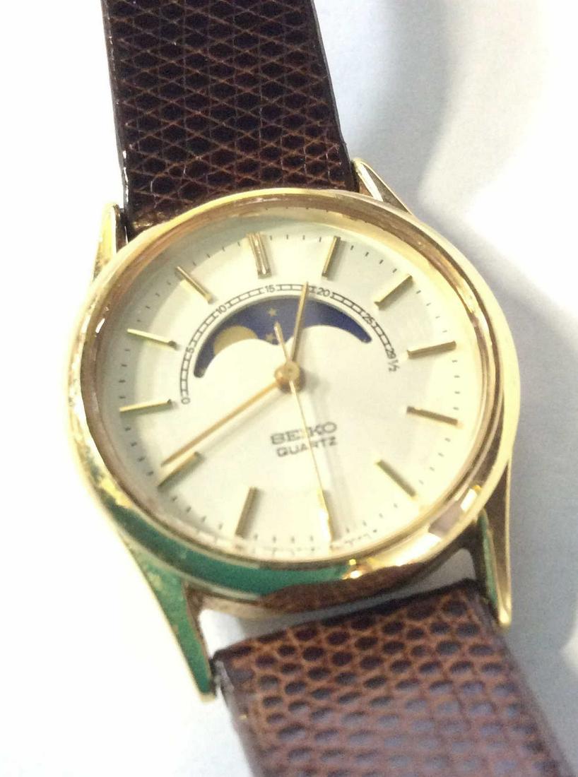Seiko Moon And Stars Gold Tone Leather Watch: Brown leather band 14 mm,, 7.5 in, gold tone watch and buckle. Watch Face 1 in. Backside is stainless steel and reads numbers 2A24-0048 B3 7D0402. Seiko Quartz, Front reads Japan 2A24 0040R Ladies Wri