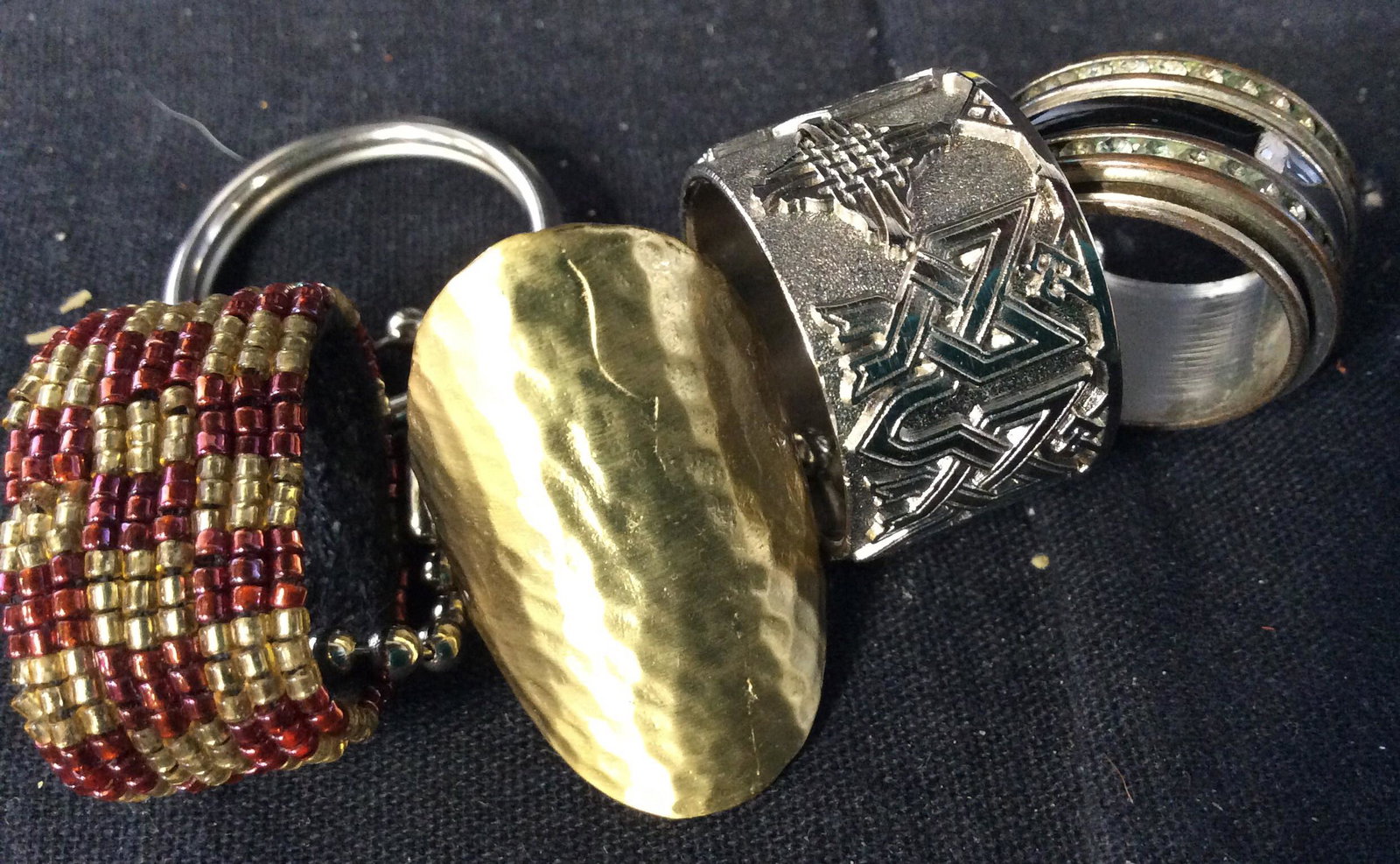 Lot 4 Fashion Jewelry, Statement Rings: Ladies Checkered bead ring, fits size 6, 7. Hammered gold tone cocktail metal ring, Sz 8. Ladies blue enamel, rhinestone ring, app Sz 6-6.5 Men’s wide embossed ring, app Sz 12. , .5 in wide. Ladies 