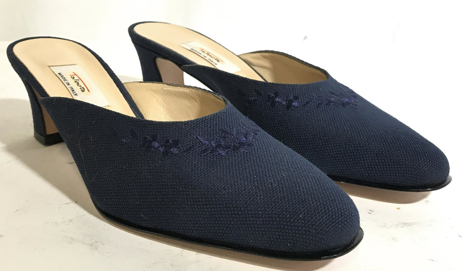 TALBOTS Women’s Heels Size 8: Undersides of shoes reads MADE IN ITALY. Sole of shoe has tag which reads TALBOTS. Shoes are navy blue toned with floral and leaf detail near toe. Shoes have 2 inch high heel. Shoes have leather sole 