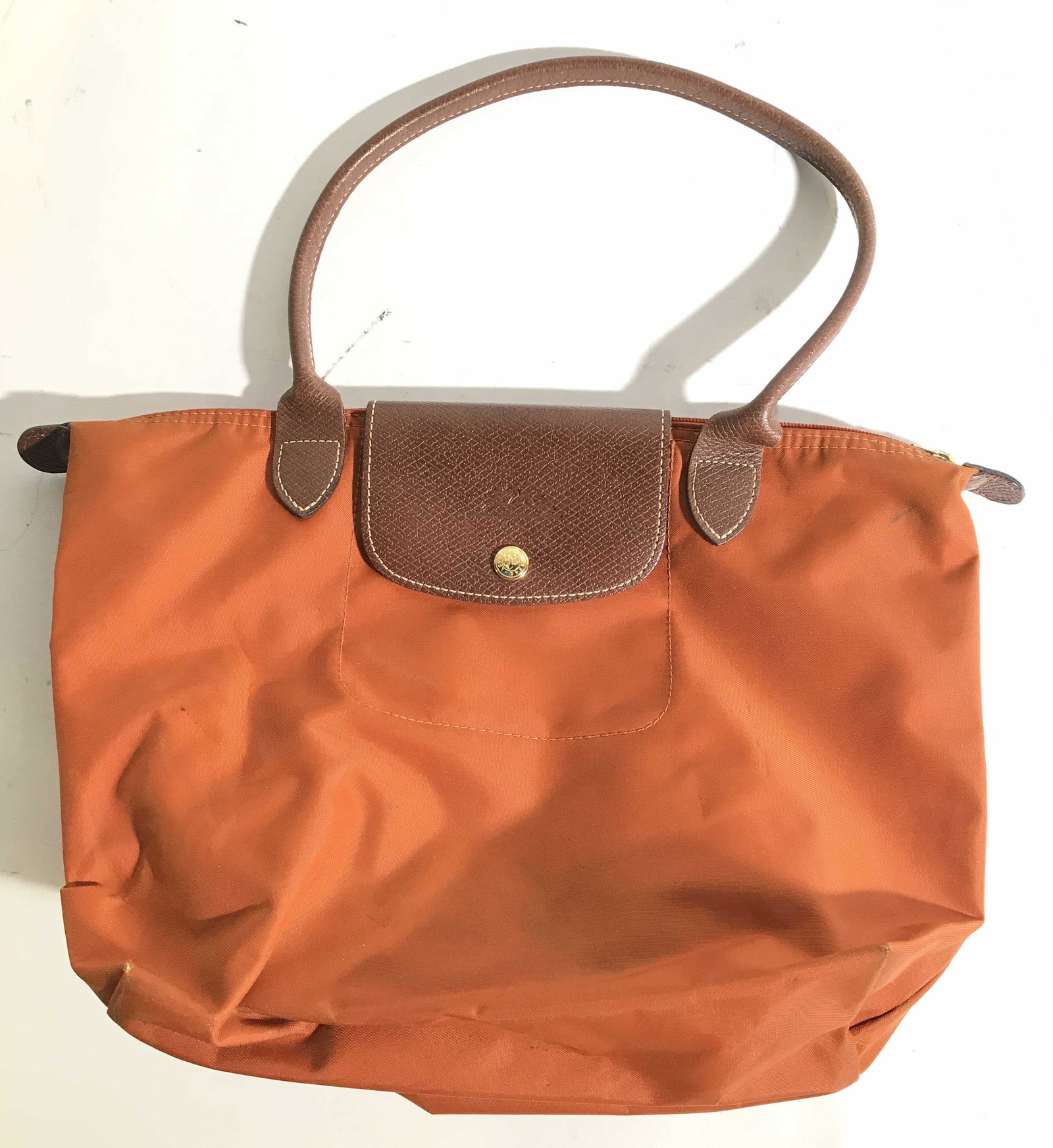 Vintage LONGCHAMP Handbag: Handbag is orange toned with brown toned leather strap, & button flap. Piece has gold toned buttons and zipper. Zipper reads LONGCHAMP 1948 . piece measures approximately 16 inches long 11 inches tall