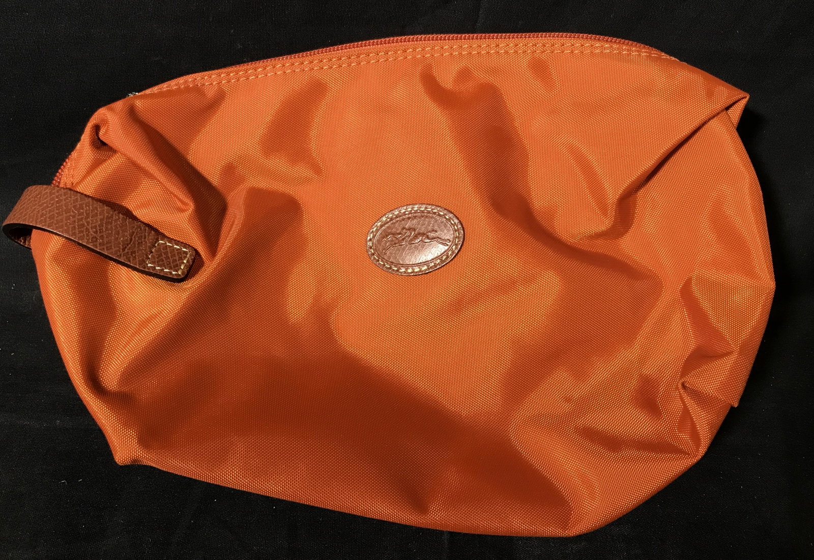 Longchamp Duck-cloth Bag: Longchamp Duck-cloth bag, made of a burnt orange water proof material, includes a small strap to the left side strap, no lining to bag, bag measures approximately 12 inches long, brown leather label t