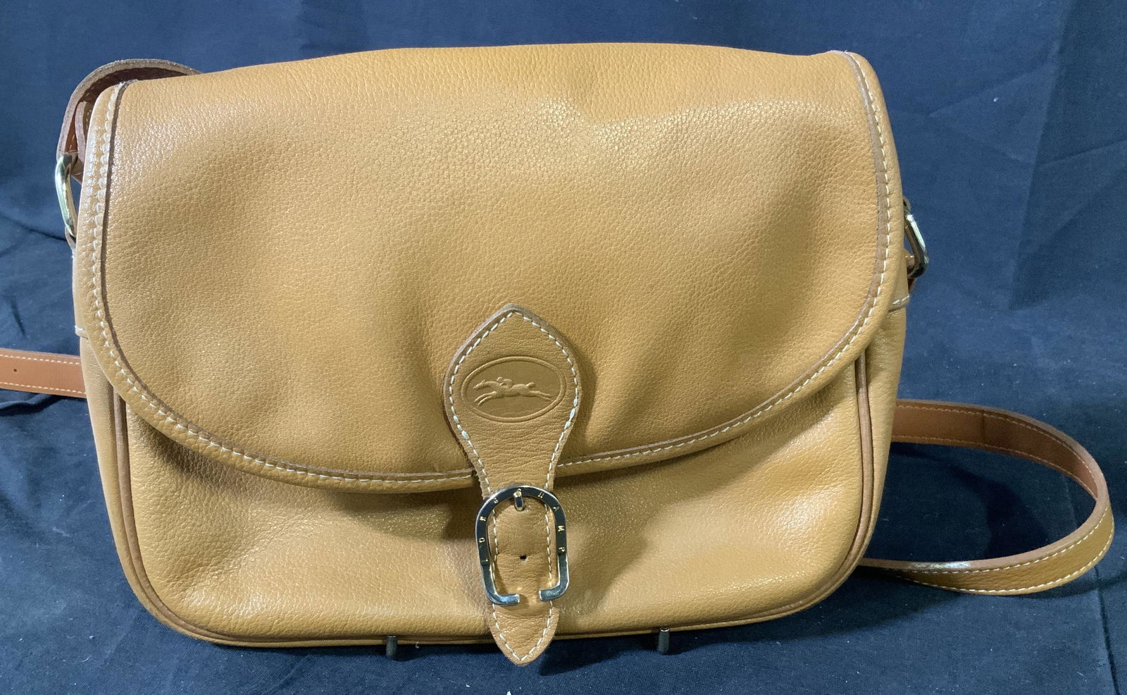 Vintage Longchamp Purse in Tan, Paris: Longchamp vintage purse, light brown with light stitching and a false buckle closing that reveals itself to be a button enclosure, adjustable strap of same material and stitching, one large open space
