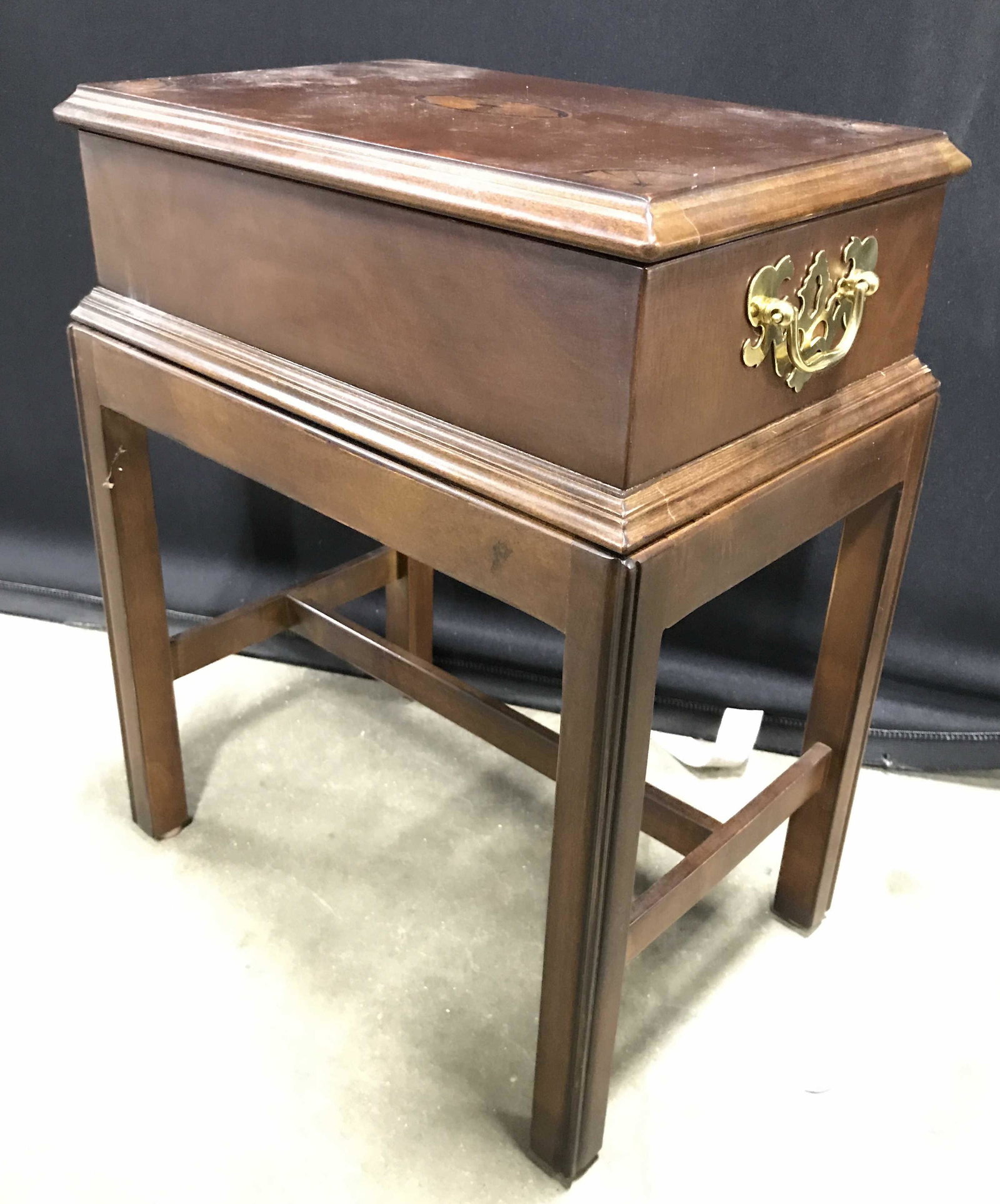 Vintage Wooden Storage Chest Side Table: Side table is vintage and wooden. Tabletop flips open to reveal storage area. Piece has 2 gold toned metal handles possibly brass. Tabletop appears to possibly have inlay detail. Legs have stretchers 