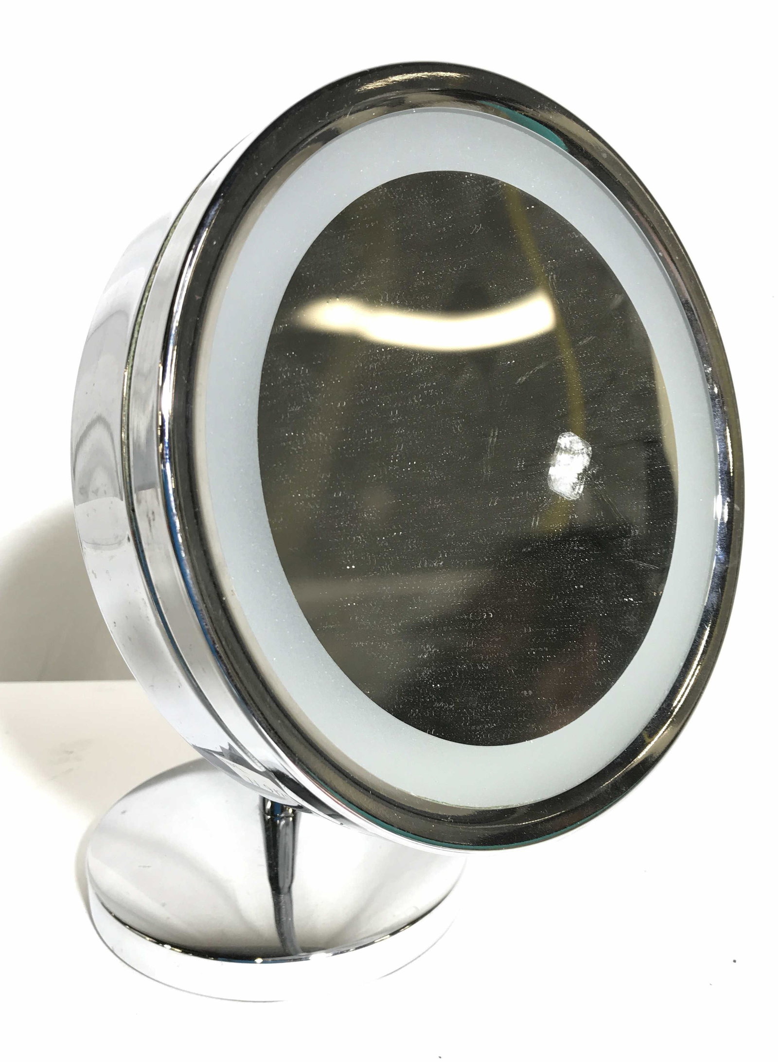 WINDMERE PRODUCTS Magnifying Makeup Mirror: Tag on backside reads WINDMERE PRODUCTS. Piece appears to be chrome. Mirrored surface is circular. Piece has ring light around mirrored surface. Piece measures approximately 12 inches tall 8 inches wi