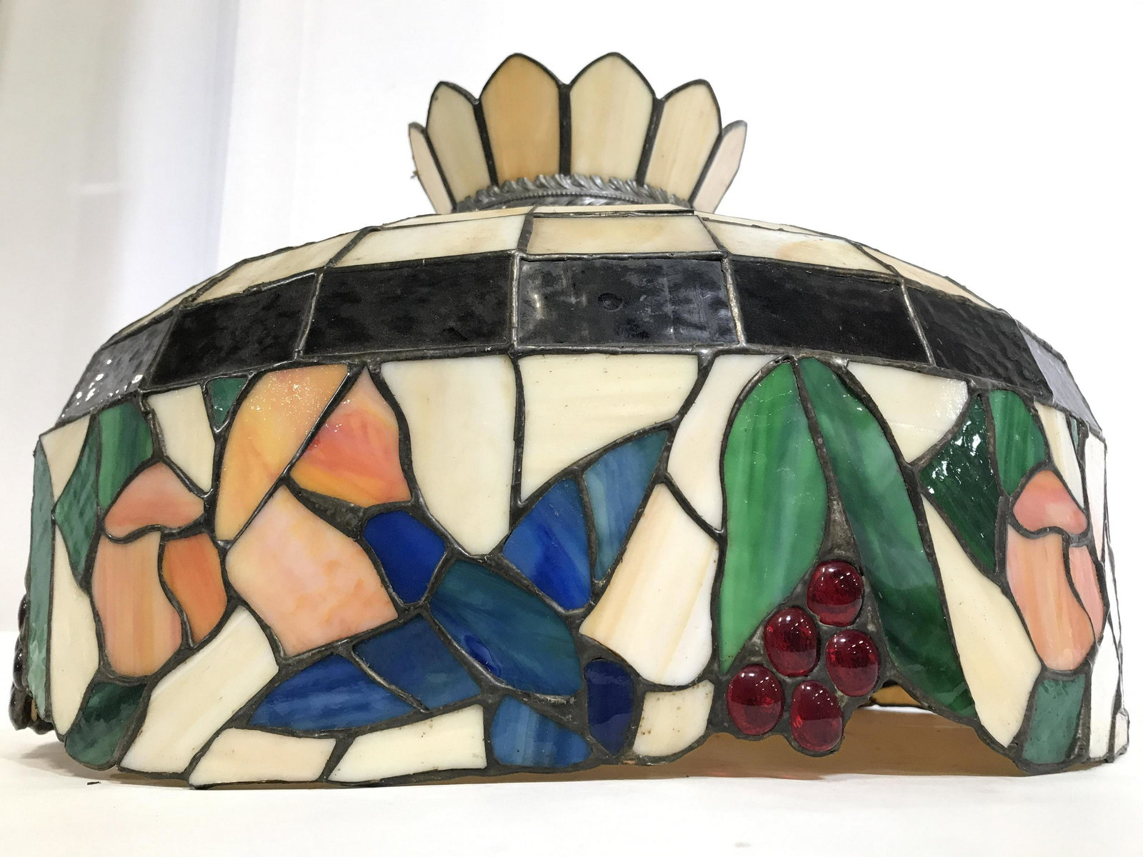 Tiffany Style Multi Toned Ceiling Lamp: Ceiling lamp is Tiffany Style. Piece has stained glass style. Piece has floral, fruit and leaf detail. Piece has 2 bulb sockets. Piece measures approximately 20 inches wide 13 inches tall. Ceiling lam