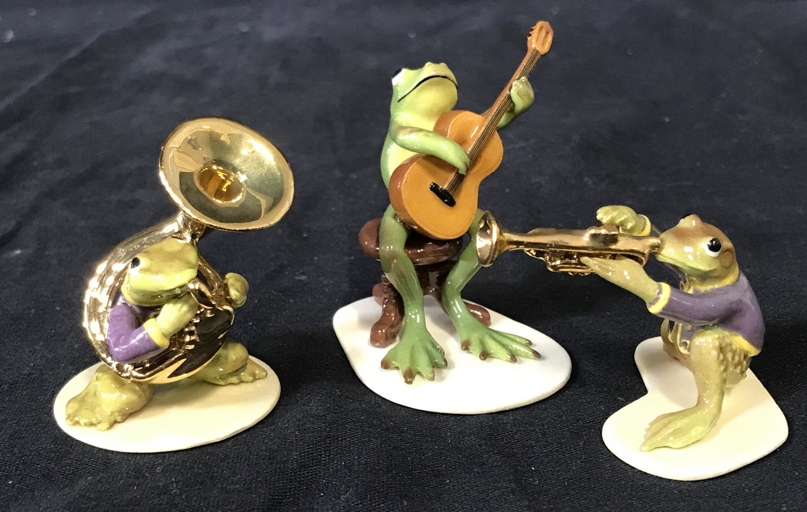 Hagen-Renaker Porcelain Frogs: Set of three Hagen-Renaker porcelain frogs, three frogs each playing different instruments atop a white stand, instruments include a tuba a trumpet and a guitar, bottom of two figures reads ‘Hagen-R