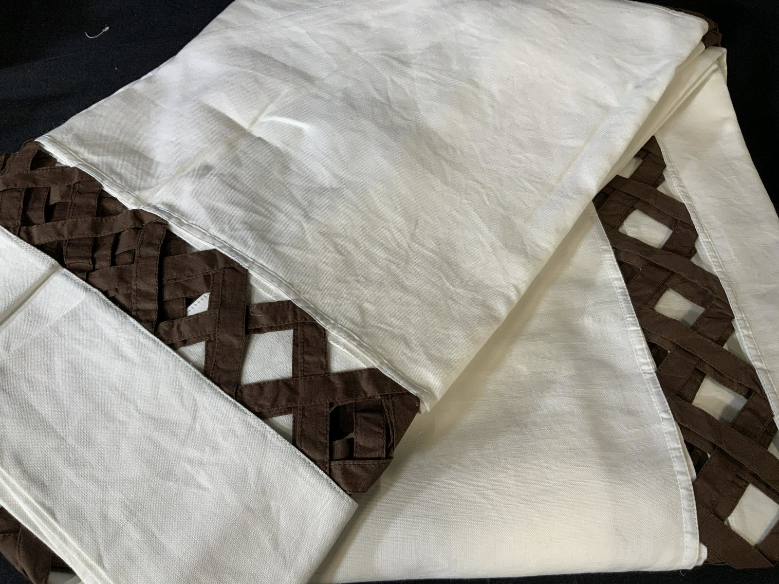Set of Two Decorative Tablecloths: Set of two large table clothes in white with a brown peek-a-boo basket pattern around the edge of the table where it hangs over the side of the table, made of linen the basket pattern is in a coffee b