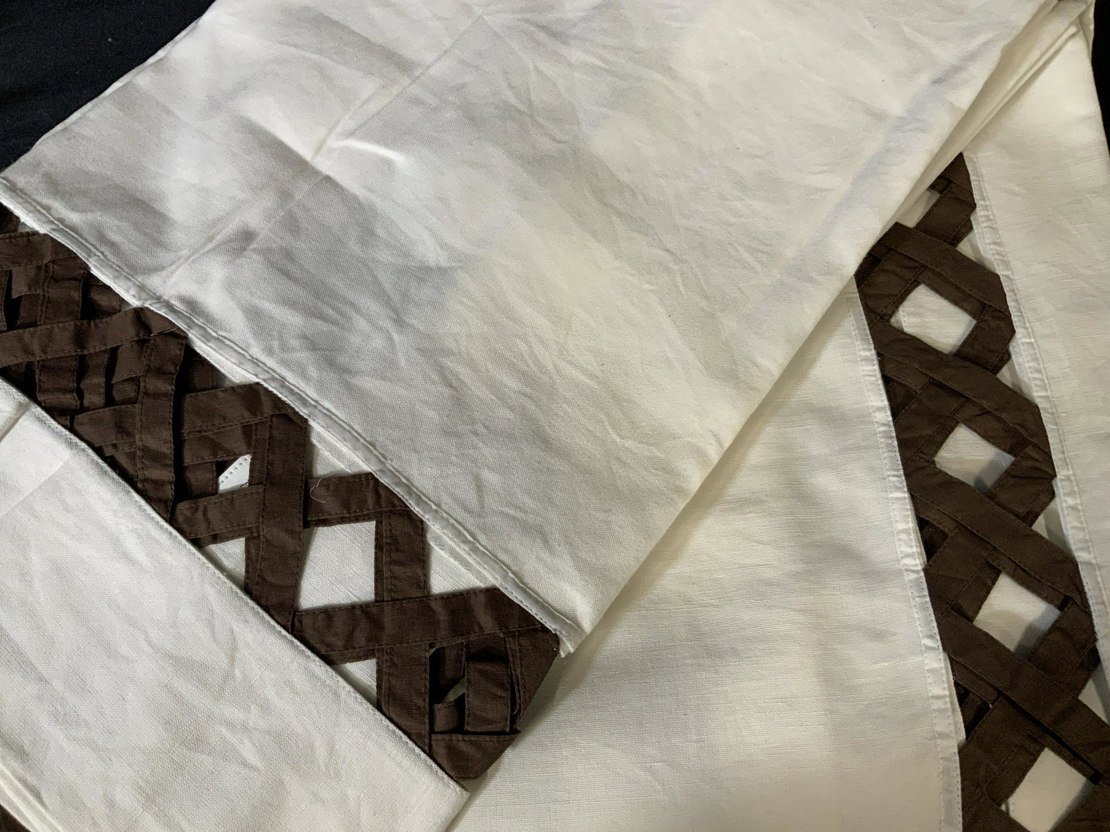 Set of Two Decorative Tablecloths: Set of two large table clothes in white with a brown peek-a-boo basket pattern around the edge of the table where it hangs over the side of the table, made of linen the basket pattern is in a coffee b